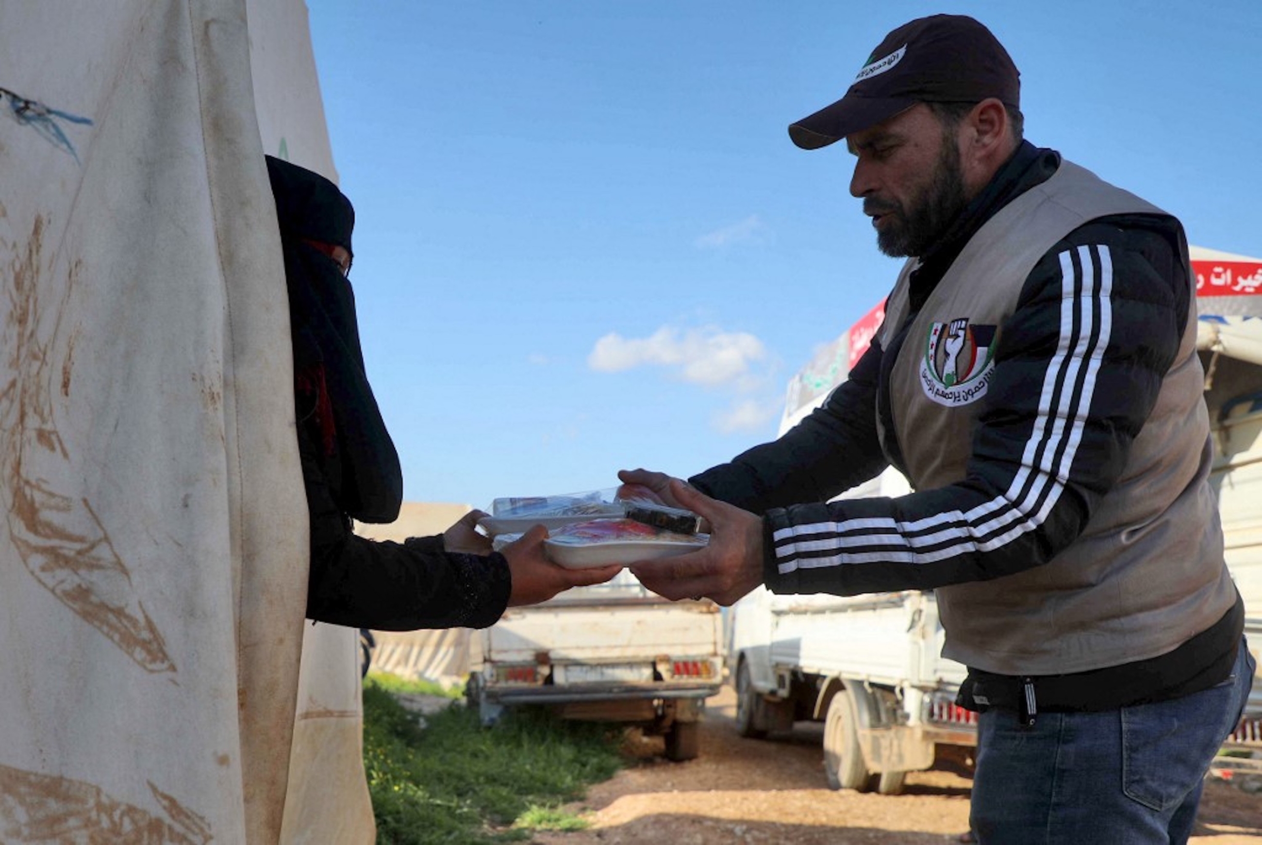 SYRIE. Un volontaire syrien distribue des assiettes de nourriture préparées par une organisation caritative locale pour l’iftar, dans un camp pour personnes déplacées par le conflit dans la ville de Sarmada, dans la province d’Idleb, au nord-ouest de la Syrie, le 13 avril 2021 (AFP)