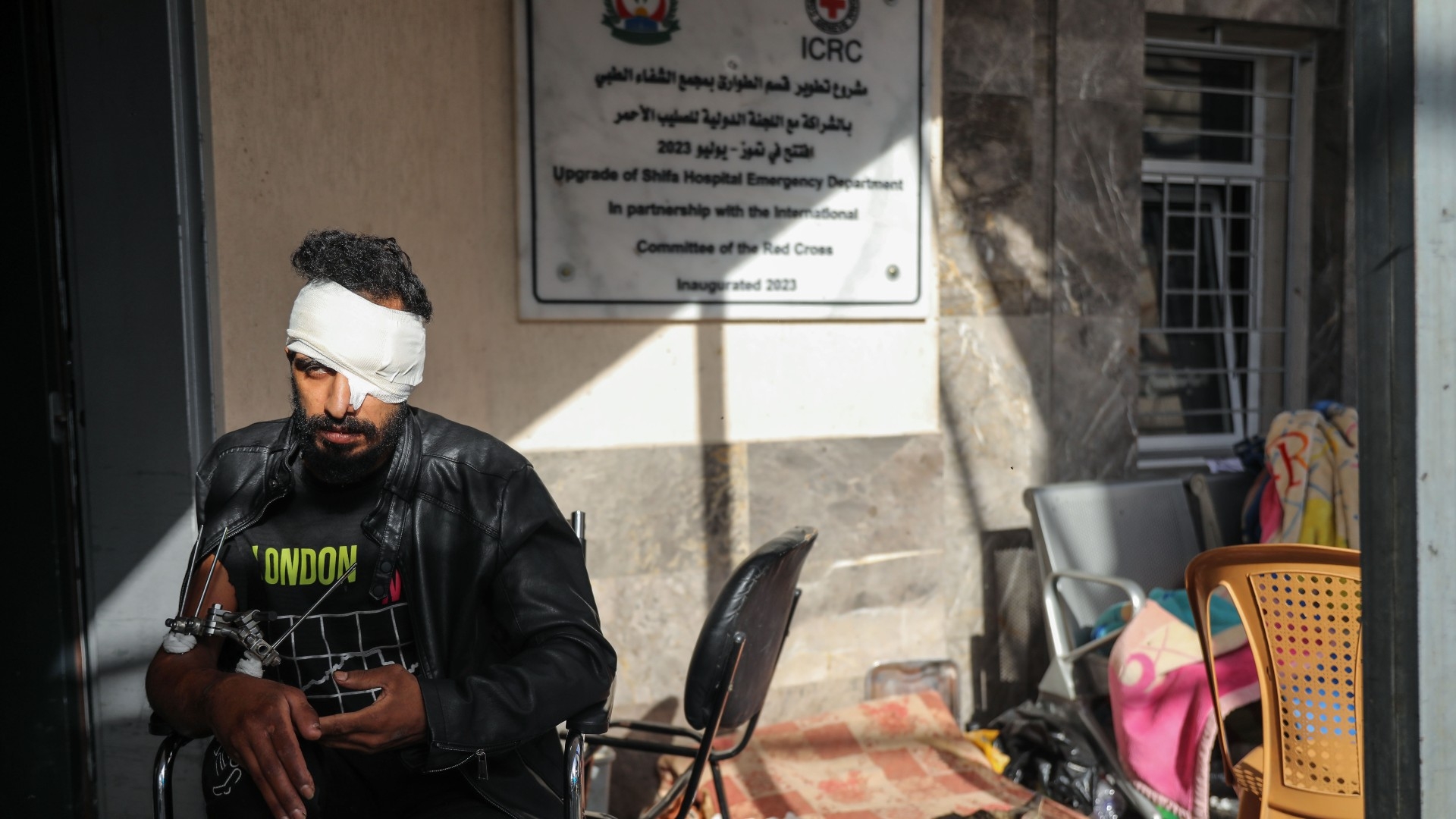 A wounded Palestinian man sitting outside the emergency department of al-Shifa hospital on 24 November 20233 (MEE)