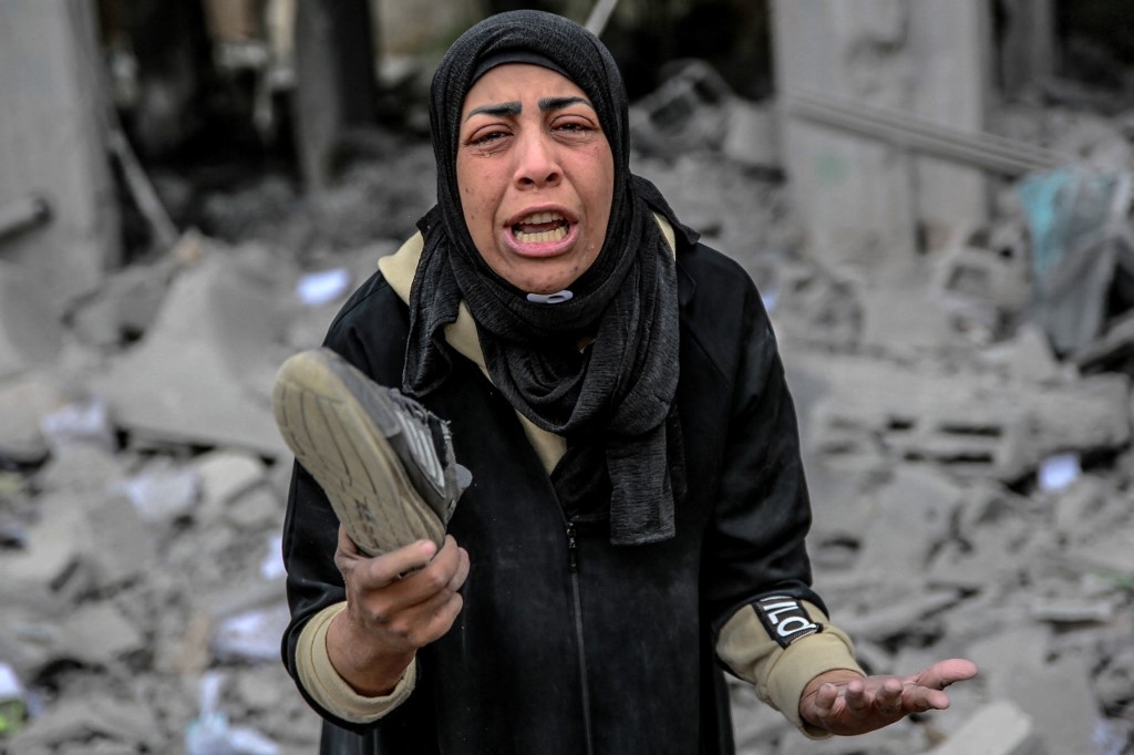 A Palestinian woman reacts as she holds her belongings next to the rubble of a building, after it was destroyed in an Israeli strike the night before, in the Rimal neighbourhood of Gaza City on March 16, 2024