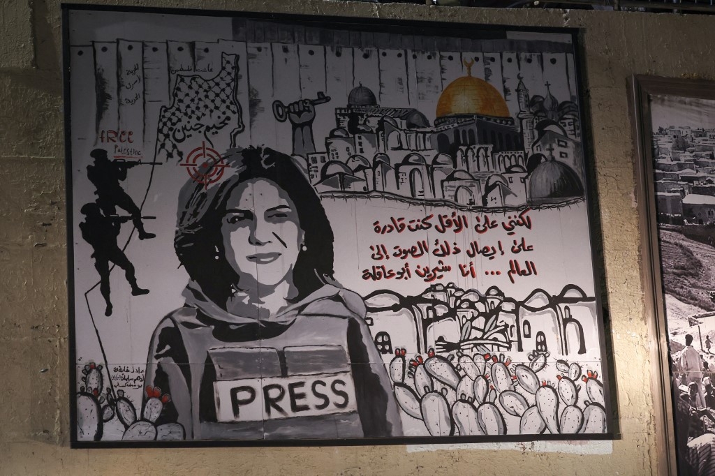 A mural depicting slain journalist Shireen Abu Akleh is illuminated with headlights on a street in the Arab town of Umm Al-Fahm on 5 September 2022 (AFP)