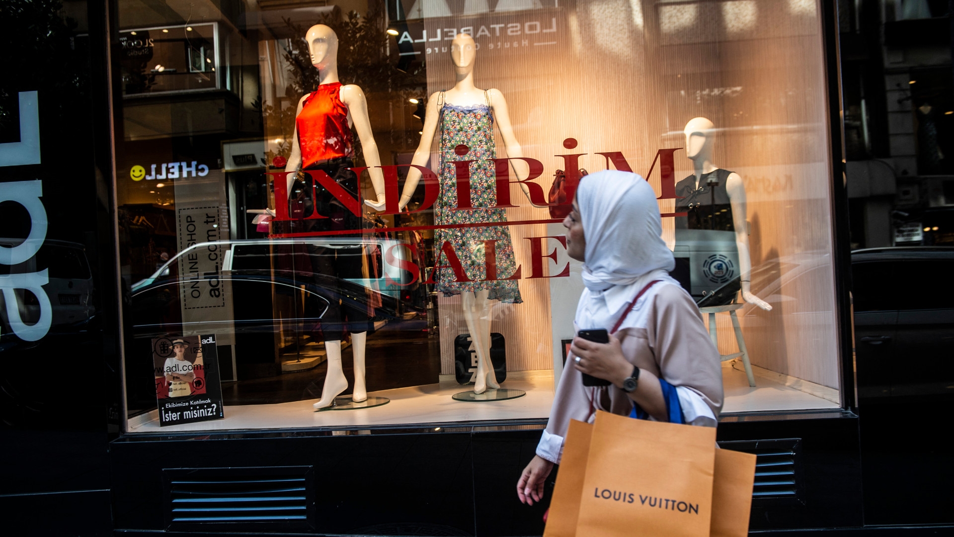 A veiled woman holding Louis Vuitton shopping bags, looks at a shop window in Istanbul on 13 August 2018 (AFP)