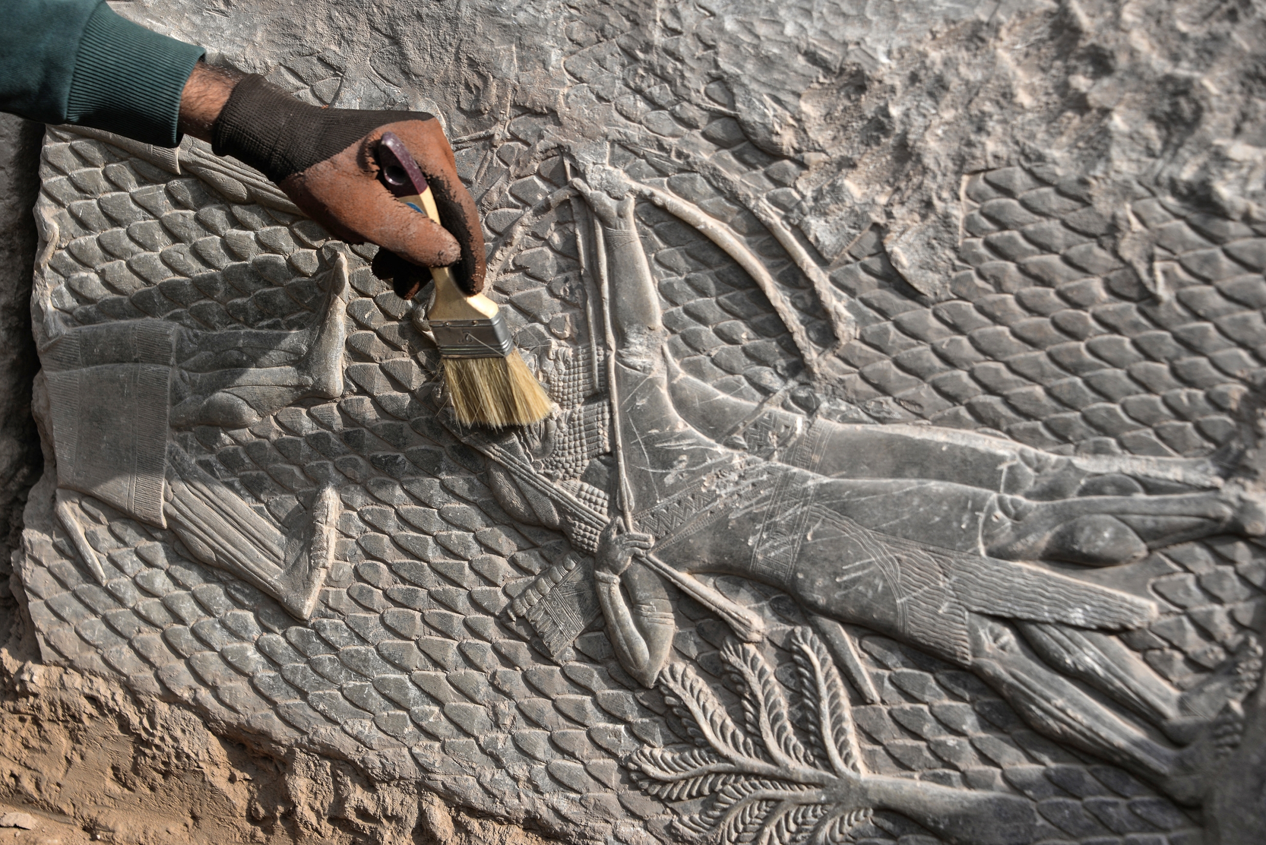 An Iraqi worker excavates a rock-carving relief recently found at the Mashki Gate, one of the monumental gates to the ancient Assyrian city of Nineveh, on the outskirts of what is today the northern Iraqi city of Mosul on October 19, 2022. Zaid AL-OBEIDI / AFP