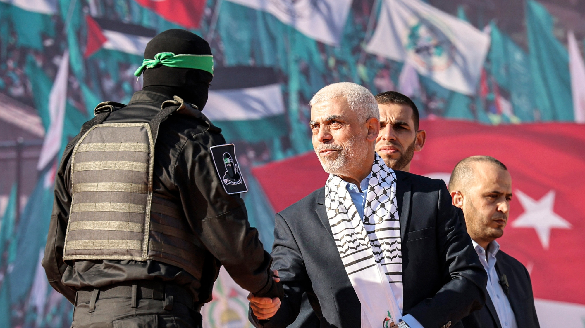 Yahia al-Sinwar shakes hands with a fighter of Hamas' Qassam Brigades during a rally marking the 35th anniversary of the group's foundation, in Gaza City on 14 December 2022 (Mohammed Abed/AFP)