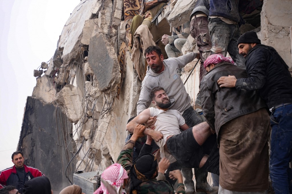 Des habitants récupèrent un homme blessé dans les décombres d’un immeuble à Jindires, dans la campagne de la ville d’Afrin, dans le nord-ouest de la Syrie, le 6 février 2023 (AFP/Rami al-Sayed)