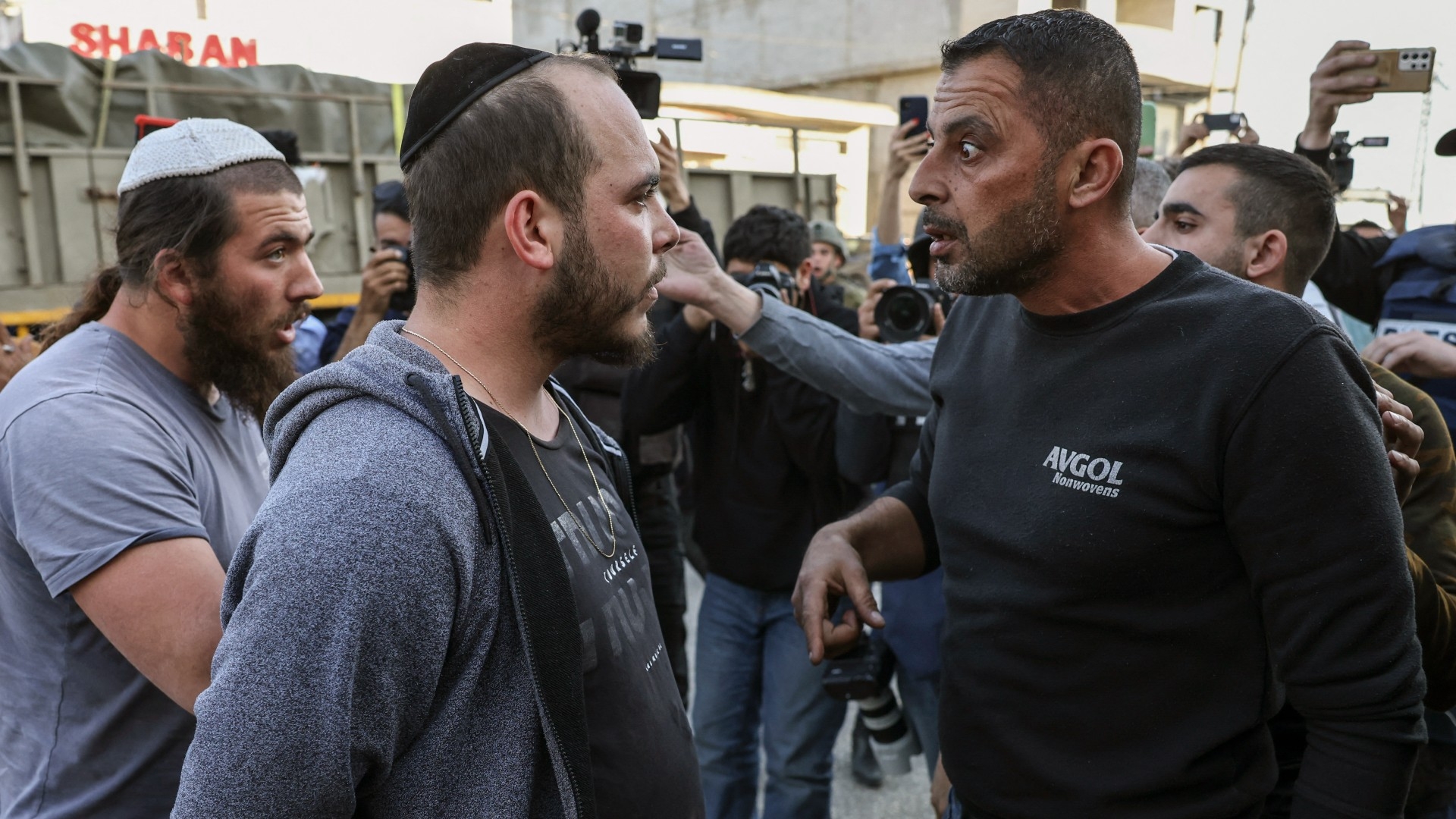 Israeli settlers confront a Palestinian in the West Bank town of Huwwara 27 February (AFP)