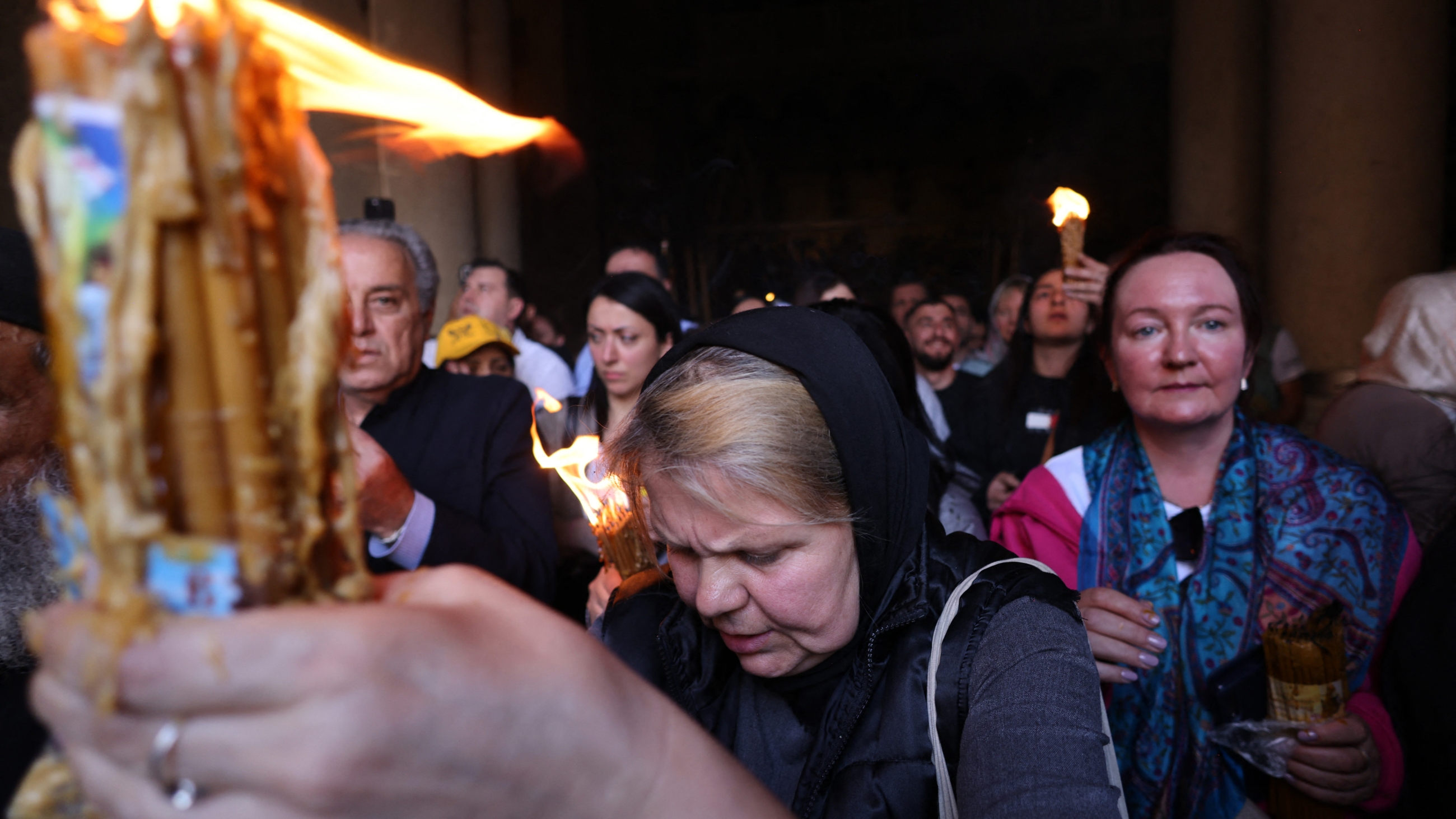 Orthodox Christians gather with lit candles during the Holy Fire ceremony at the Holy Sepulchre church in Jerusalem's Old City on 15 April 2023 (AFP)
