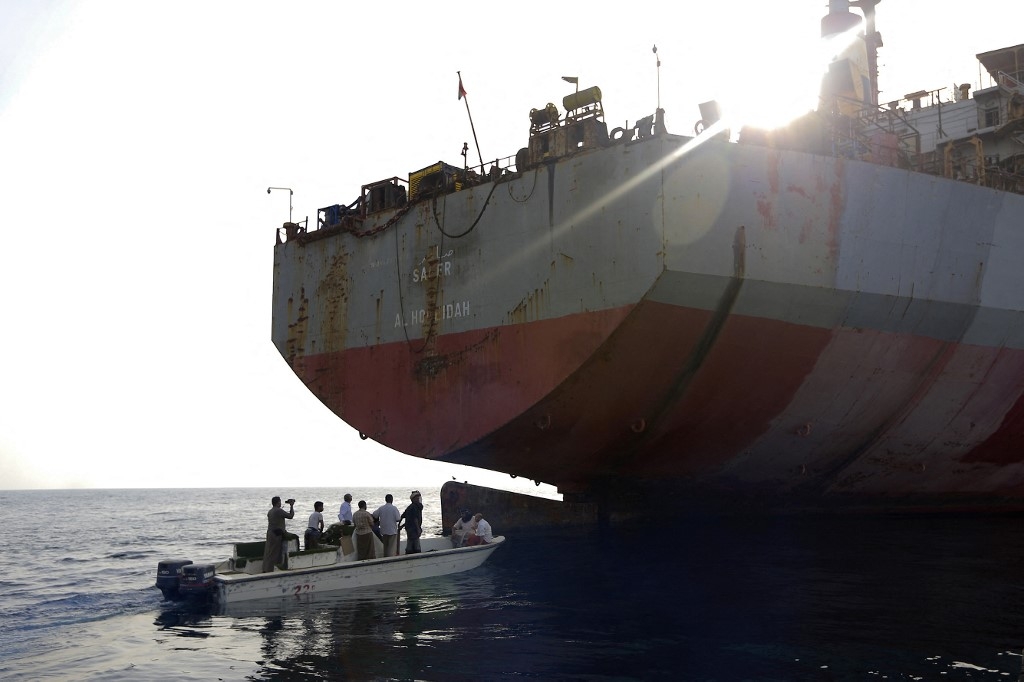 Des personnes à bord d’un petit bateau s’approchent du pétrolier FSO Safer, battant pavillon yéménite, en mer Rouge, au large de la province occidentale contestée de Hodeïda, le 15 juillet 2023 (AFP/Mohammed Huwais)