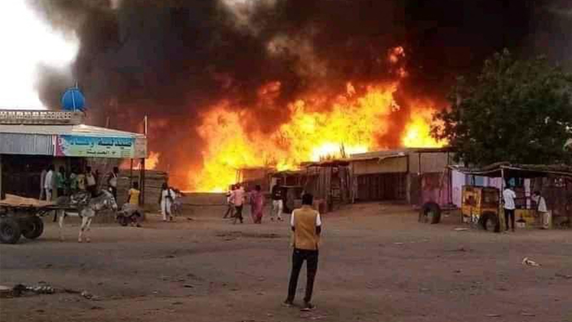 A man stands by as a fire rages in a livestock market area in al-Fasher, the capital of Sudan's North Darfur state, on 1 September (AFP)