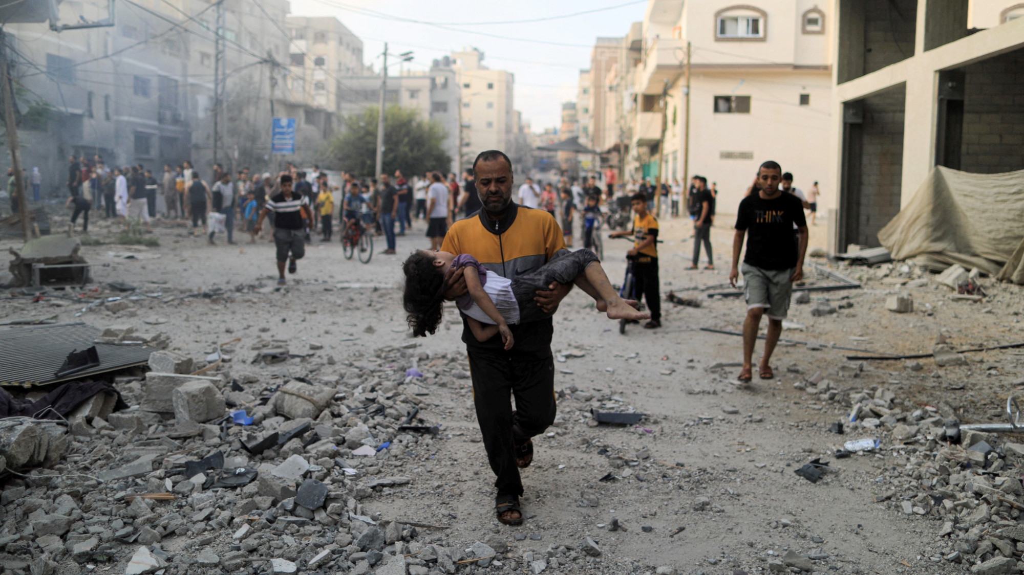 A Palestinian carries a child after an Israeli air strike in Khan Yunis in the southern Gaza Strip on 14 October 2023 (AFP)