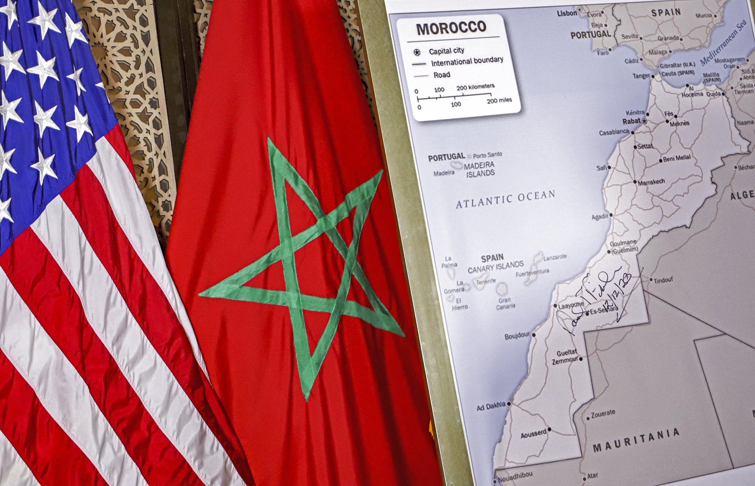Un drapeau américain et un drapeau marocain apparaissent à côté d’une carte du Maroc approuvée par le département d’État américain, reconnaissant le territoire internationalement contesté du Sahara occidental, le 12 décembre 2020 (AFP)