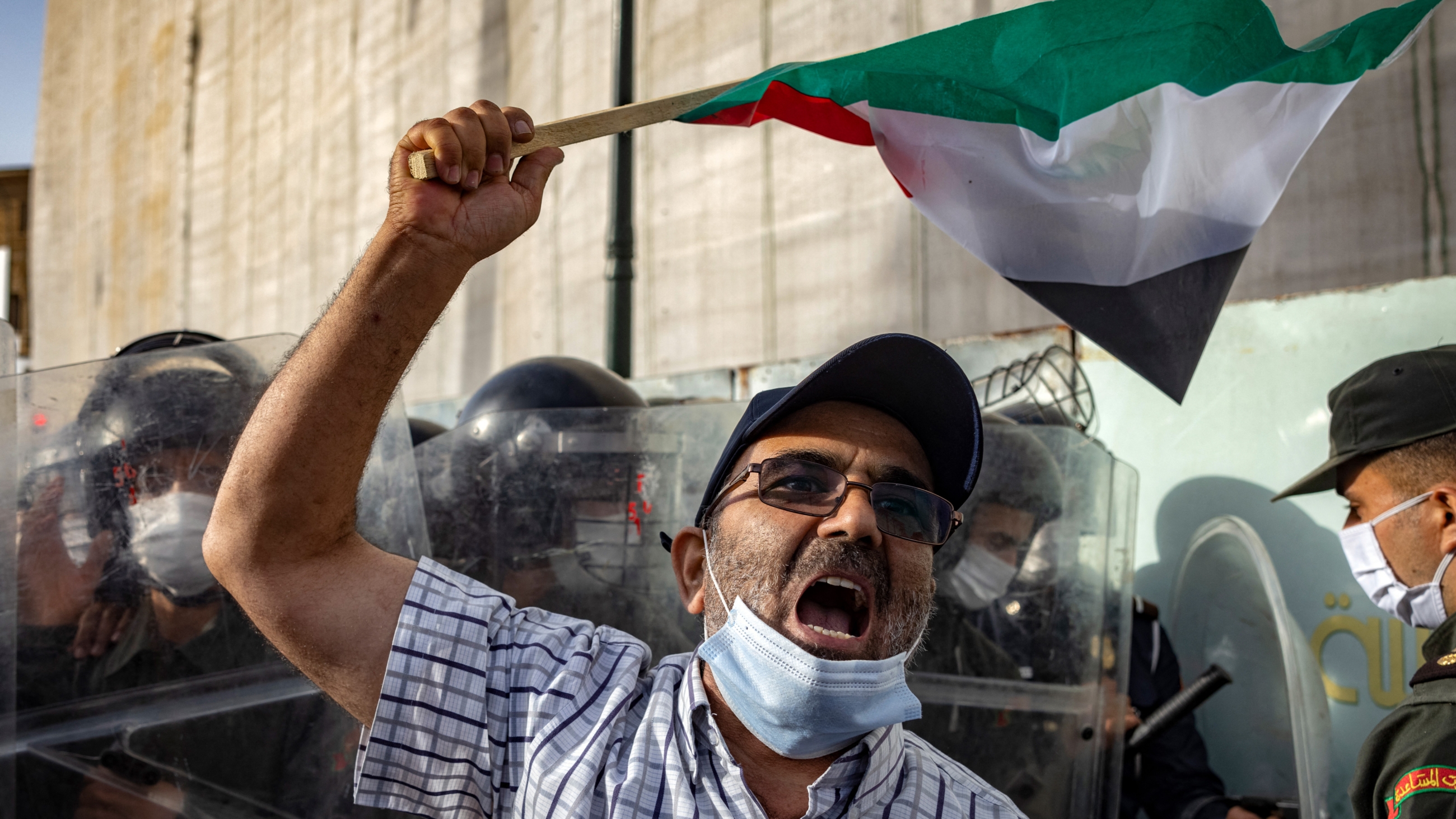 A man waving a Palestinian flag at a protest calling for an end to Israeli violence in Gaza and against the normalisation with Israel, in the Moroccan capital Rabat on 16 May 2021 (AFP)
