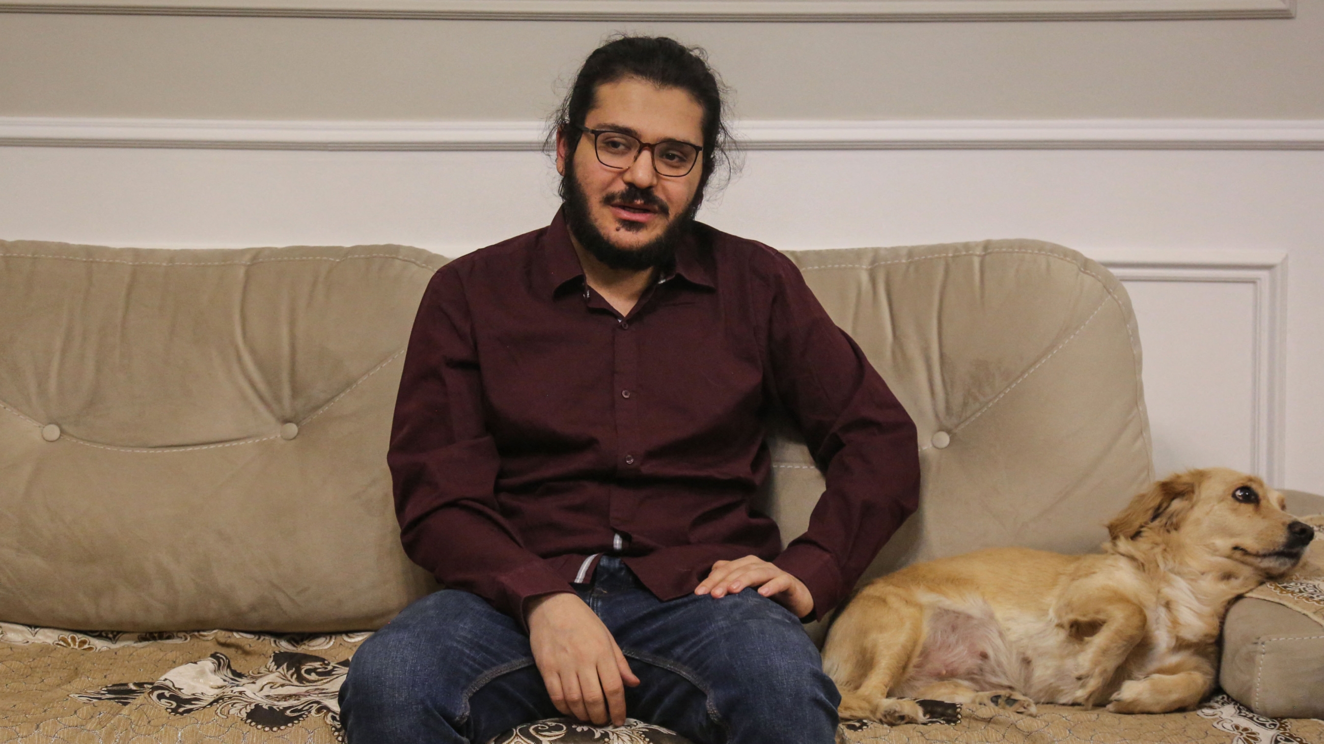 Egyptian researcher Patrick Zaki is pictured next to a dog at his family home in Cairo, on 9 December 2021 (AFP)