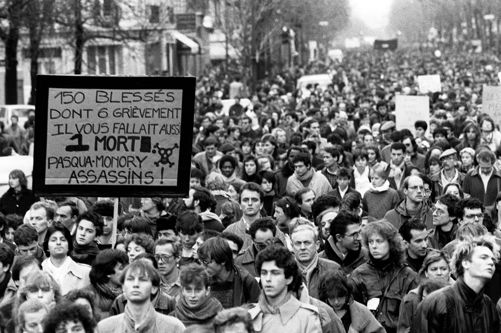 Plusieurs milliers de personnes manifestent silencieusement, à Paris le 6 décembre 1986, de la place de la Sorbonne à l’hôpital Cochin où repose le corps de Malik Oussekine, le jeune étudiant décédé le matin même après avoir été violemment frappé par des policiers (AFP)