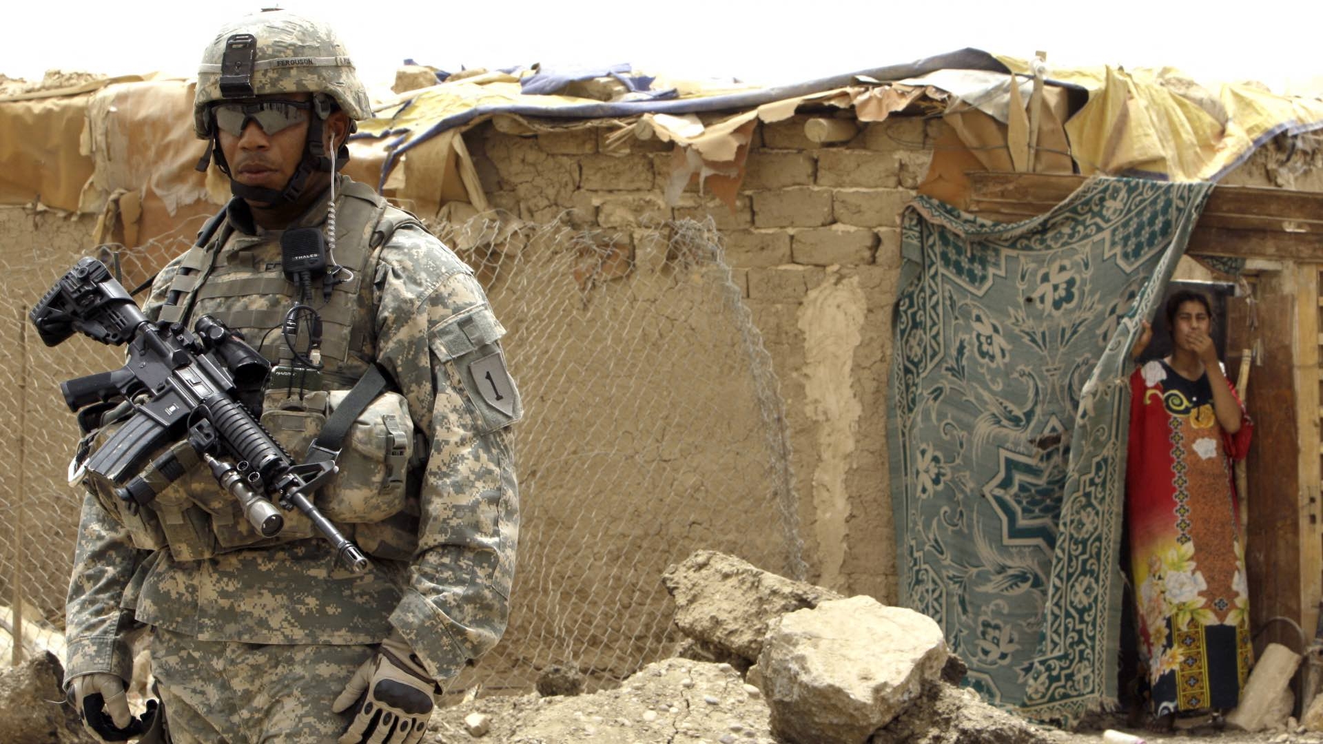 An Iraqi woman looks on as a US soldier secures the Chikuk complex in the Kadhimiya district of northwest Baghdad, on 21 July 2009.