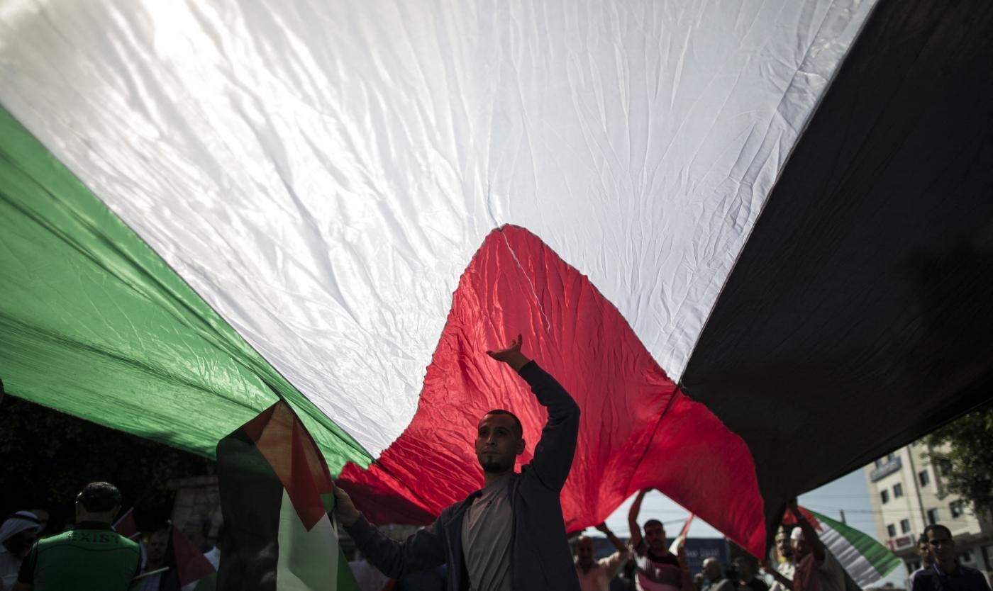 Des Palestiniens agitent des drapeaux palestiniens lors d’une manifestation contre la division et en faveur de l’unité nationale (AFP)