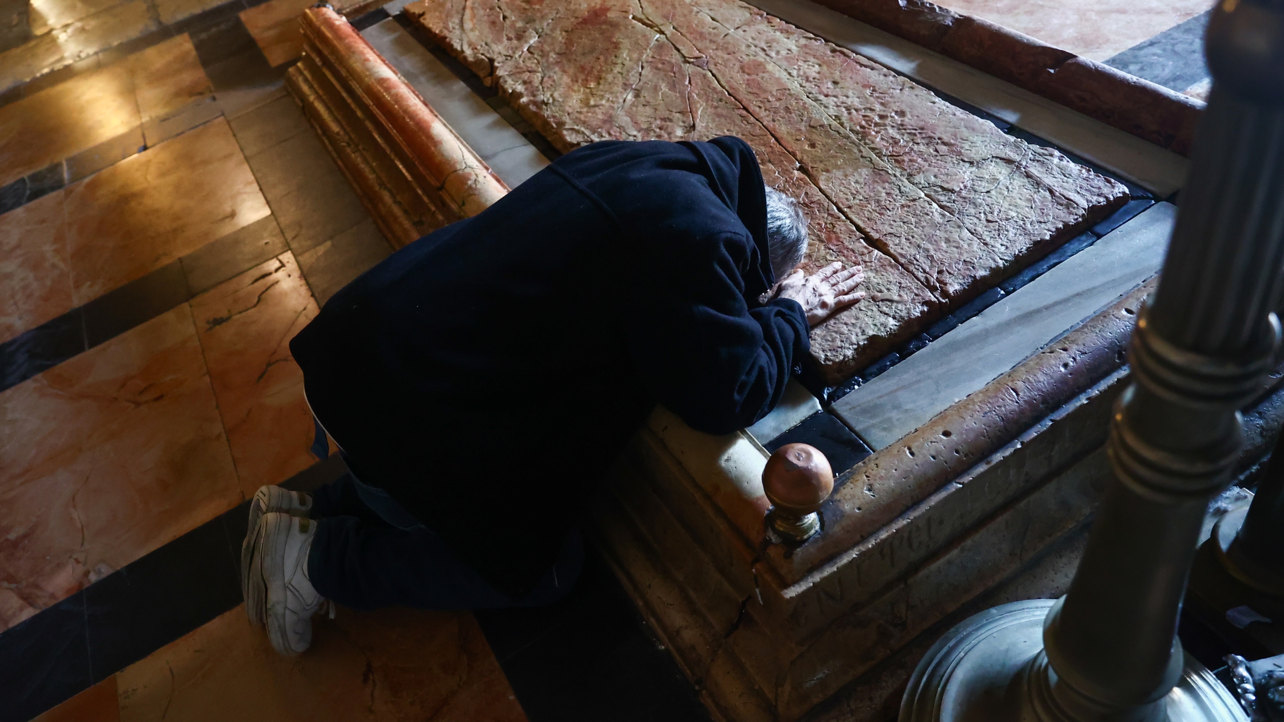 A man touches the Stone of Anointing inside the Church of the Holy Sepulchre in Jerusalem on 29 December 2022 (Reuters)