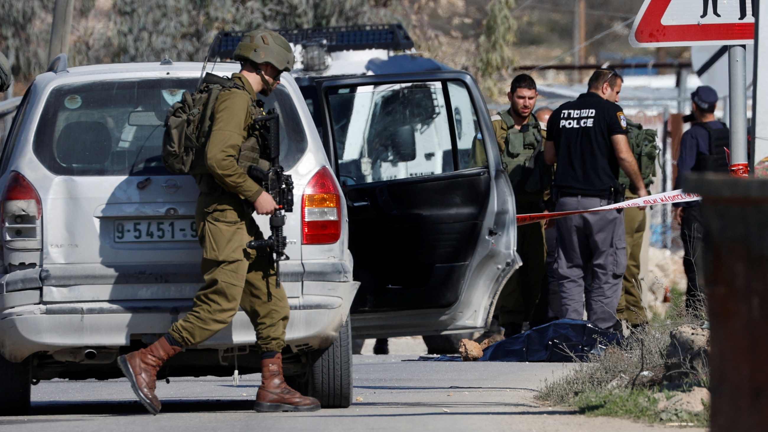 An Israeli soldier walks at the scene where Hamdi Shaker Abu Diya, 40, was shot dead by troops in near Hebron in the occupied West Bank on 17 January 2023 (Reuters)