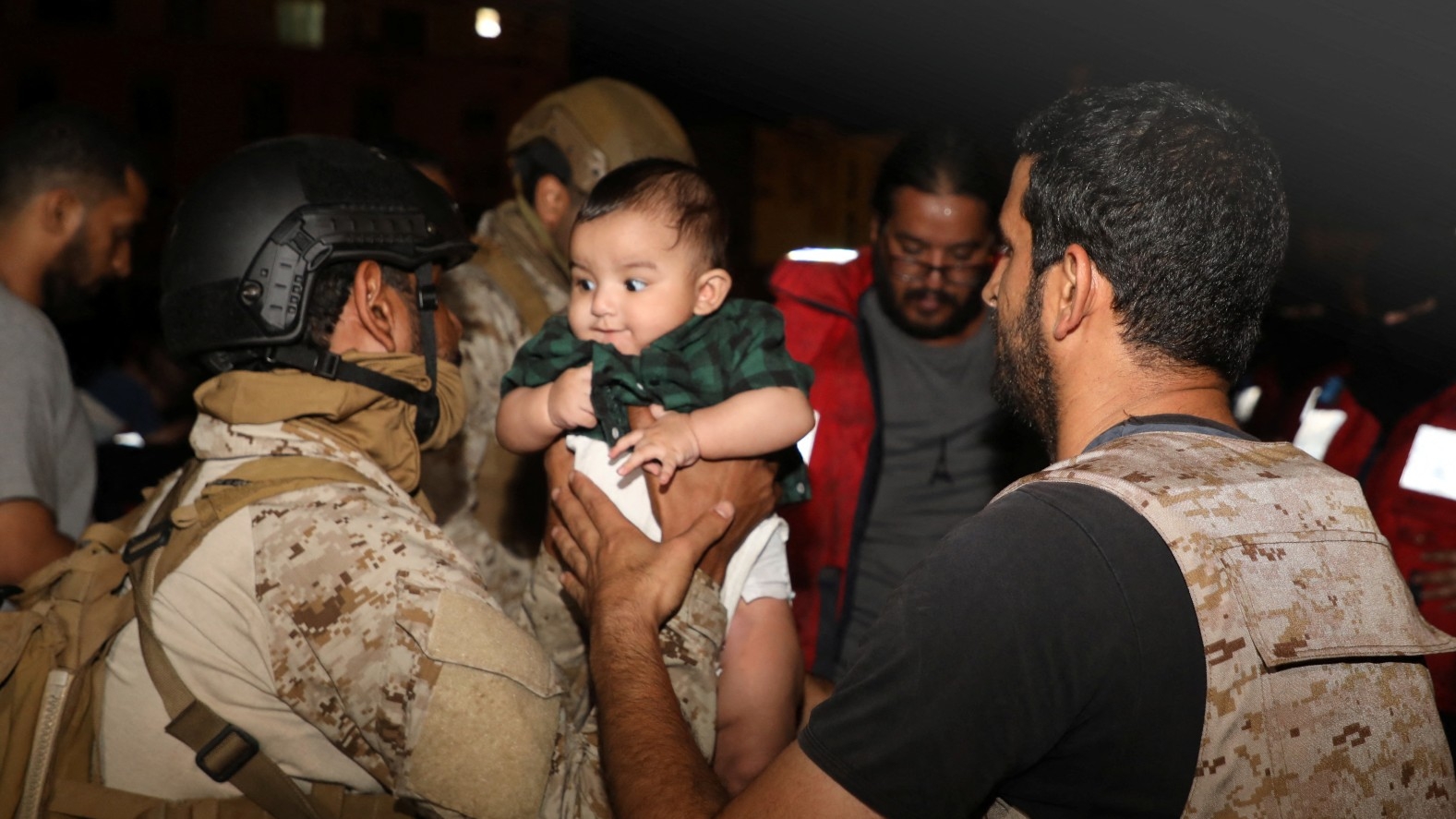 Saudi Royal Navy officers assist a child onboard their navy ship as they evacuate Saudi and other nationals are through Saudi Navy Ship from Sudan (Reuters)