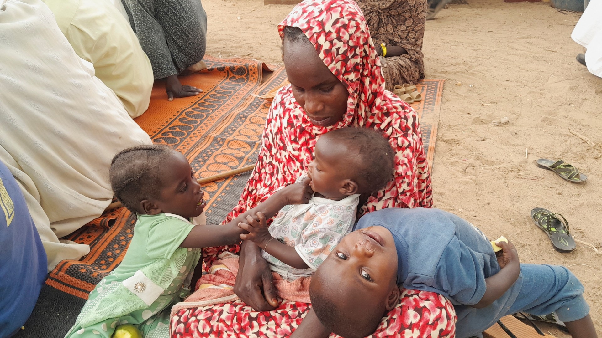 A Sudanese refugee who fled the violence is seen with her children as she gathers with other refugees near the border between Sudan and Chad, in Koufroun, Chad on 29 April (Reuters)