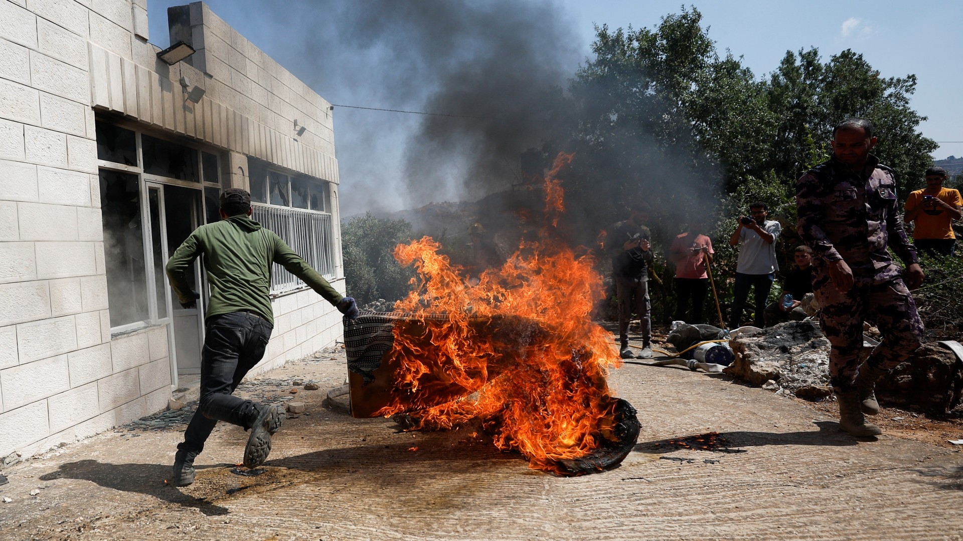 A Palestinian man runs near a burning object, after an attack by Israeli settlers, in Turmusaya, 21 June (Reuters)