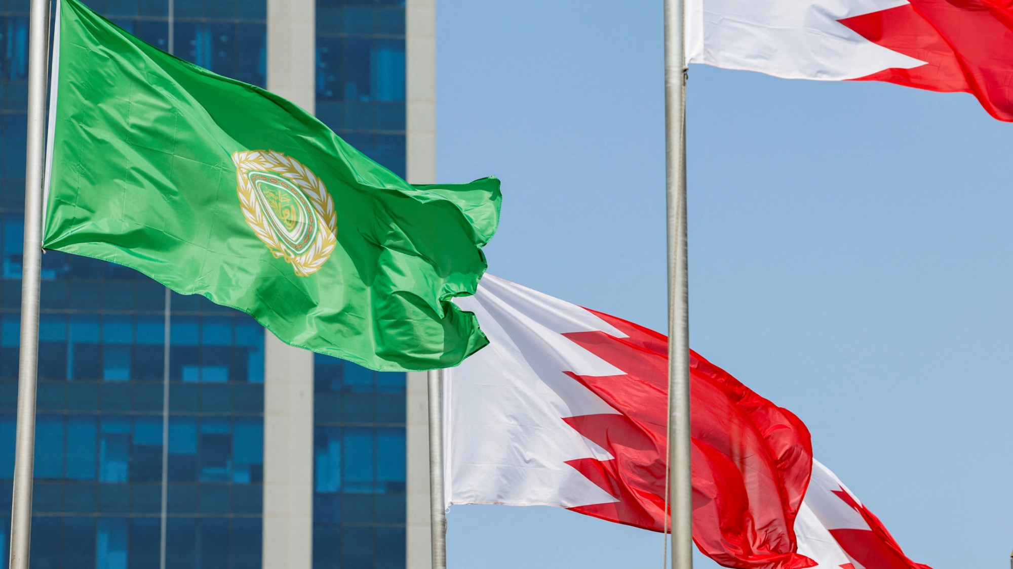 Bahraini flags and a flag with the logo of the 33rd Arab Summit are displayed ahead of the summit, which will take place in Manama, Bahrain, 14 May 2024 (Reuters/Hamad I Mohammed)