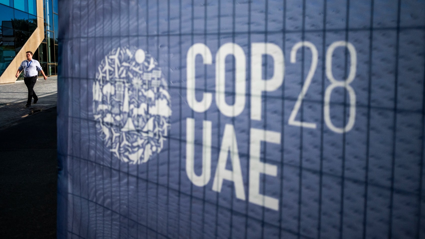 Un homme passe à côté d’un panneau de la COP 28 sur les lieux du sommet de l’ONU pour le climat à Dubaï, le 30 novembre 2023 (AFP)