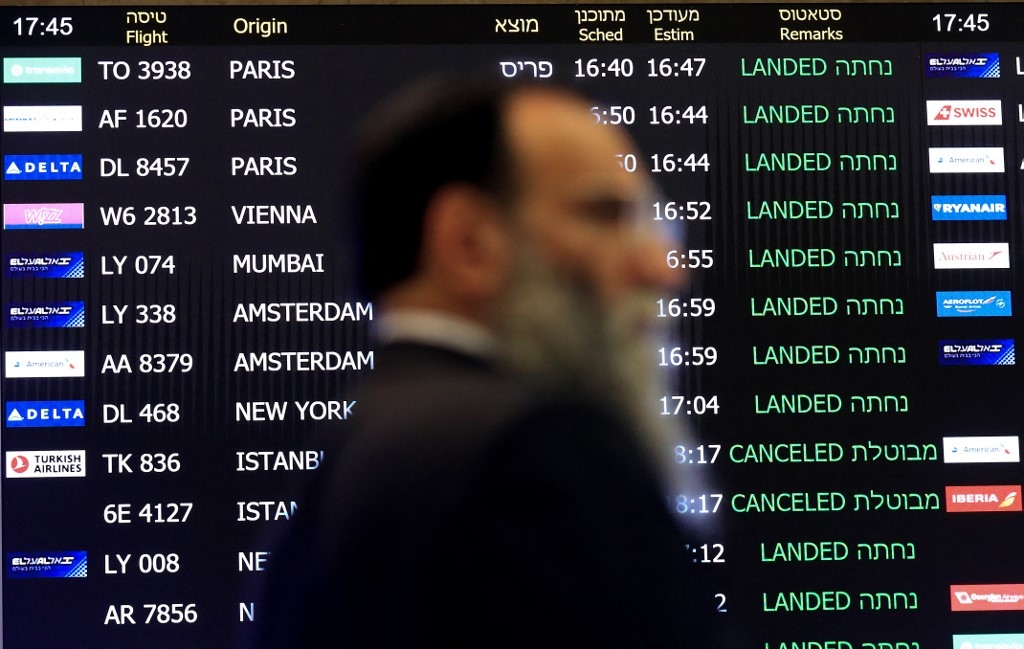 A man walks past a screen announcing arrivals at Israel's Ben Gurion airport on 4 March 2020 (AFP)