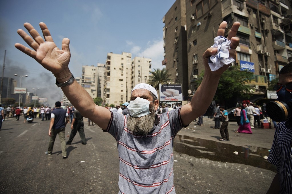 A supporter of Egypt's ousted President Mohamed Morsi gestures during clashes with riot police on a street leading to Rabaa Square in Cairo on 14 August 2013 (AFP)