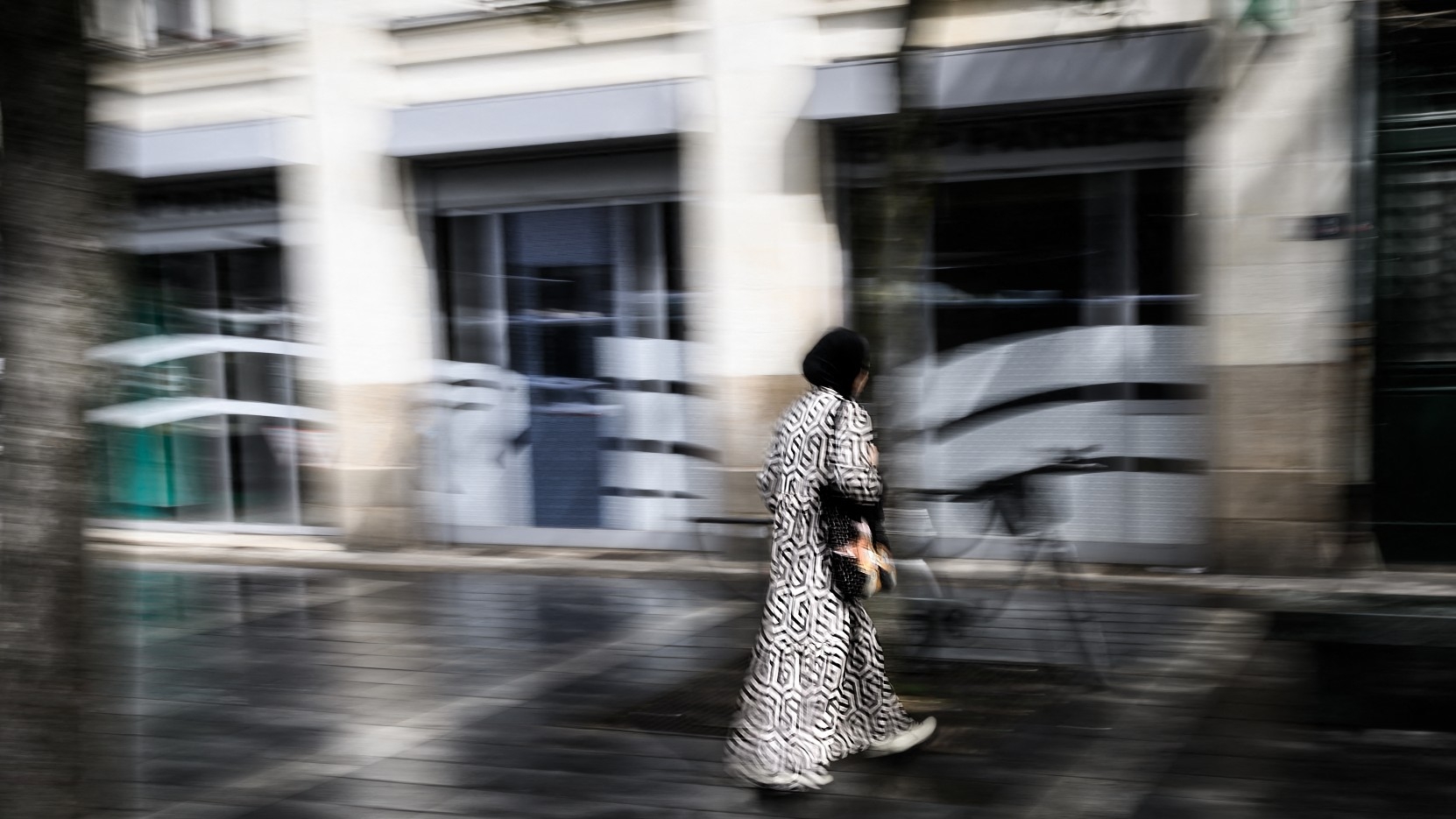 A young woman wears an Abaya as she crosses a street in Nantes, western France on 31 August, 2023 (AFP)