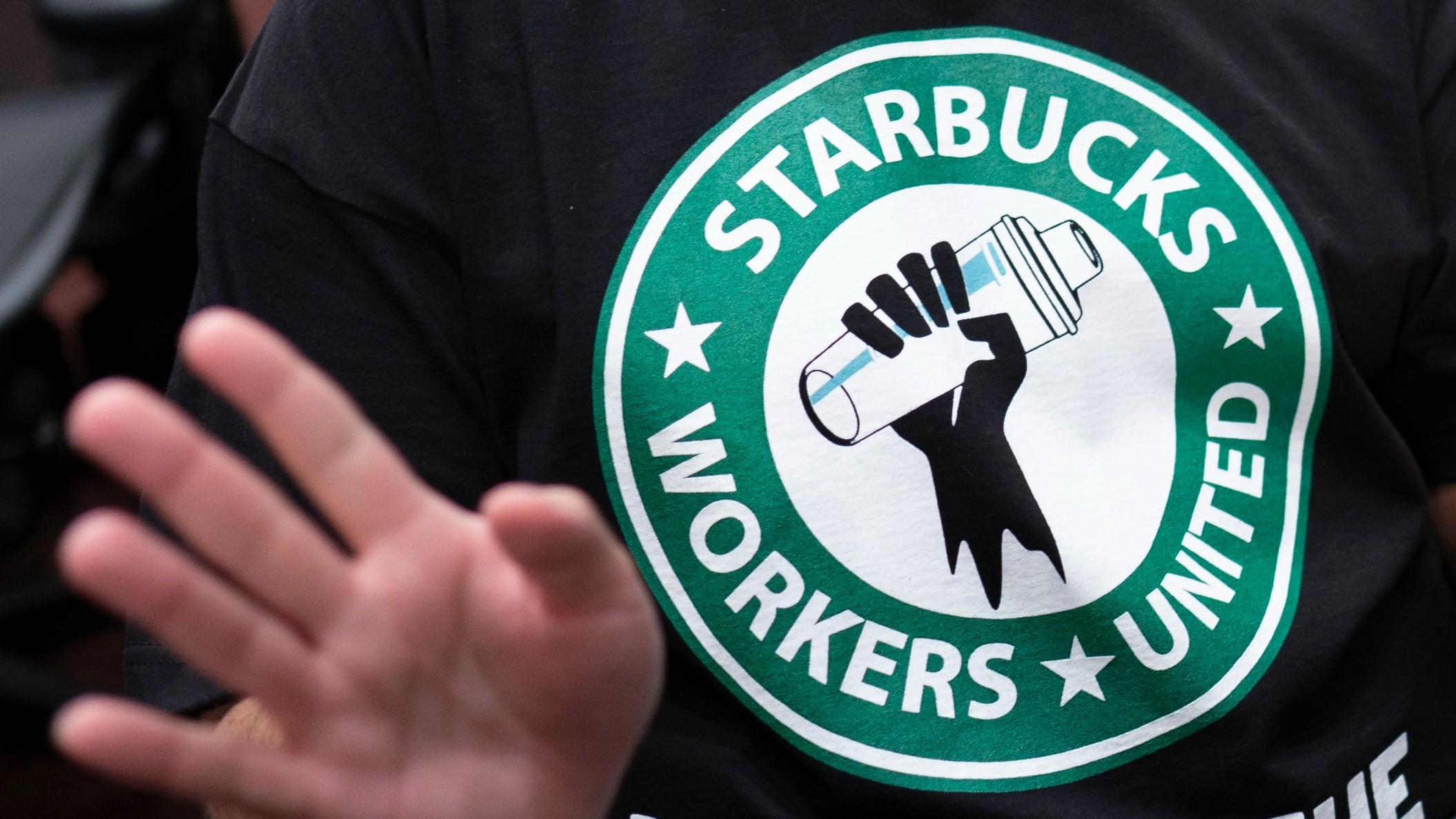 The Starbucks Workers United logo on the shirt of a former Starbucks employee attending a hearing at the Capitol in Washington, on 29 March (AP)