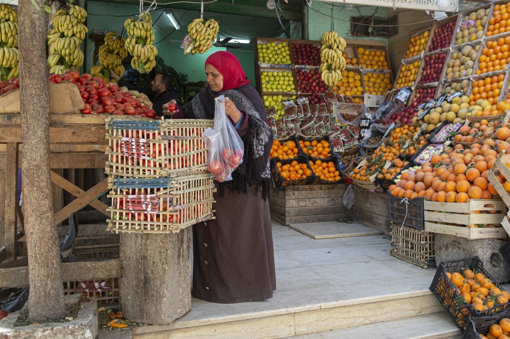 An Egyptian woman shops at a Cairo market, 17 March 2022. By the end of this year, the country's predicted foreign debt will mean that each Egyptian will owe nearly $4k (AFP)