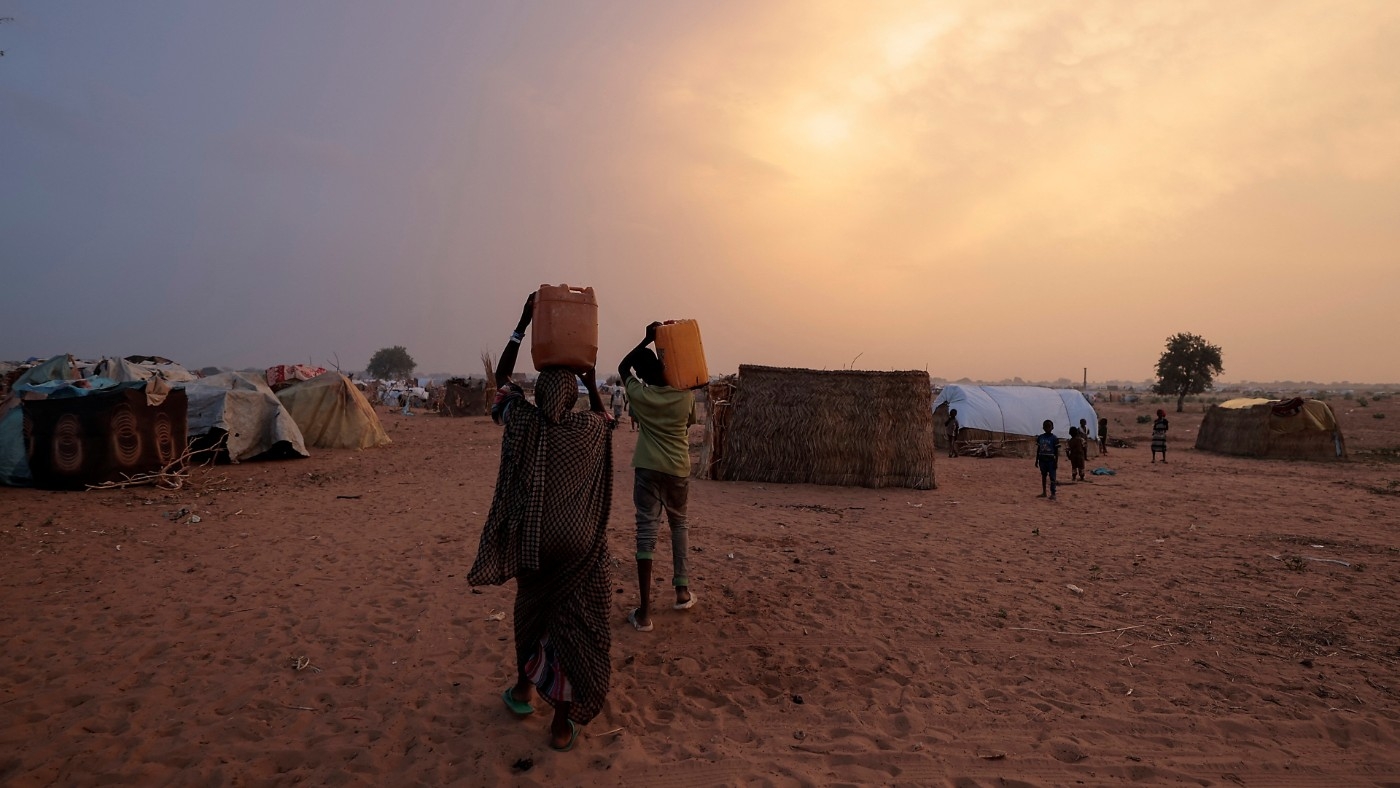 Sudanese people who fled the conflict in Sudan's Darfur region, carry their jerrycans of water as they walk toward their makeshift shelters in Adre, Chad 21 July (Reuters)