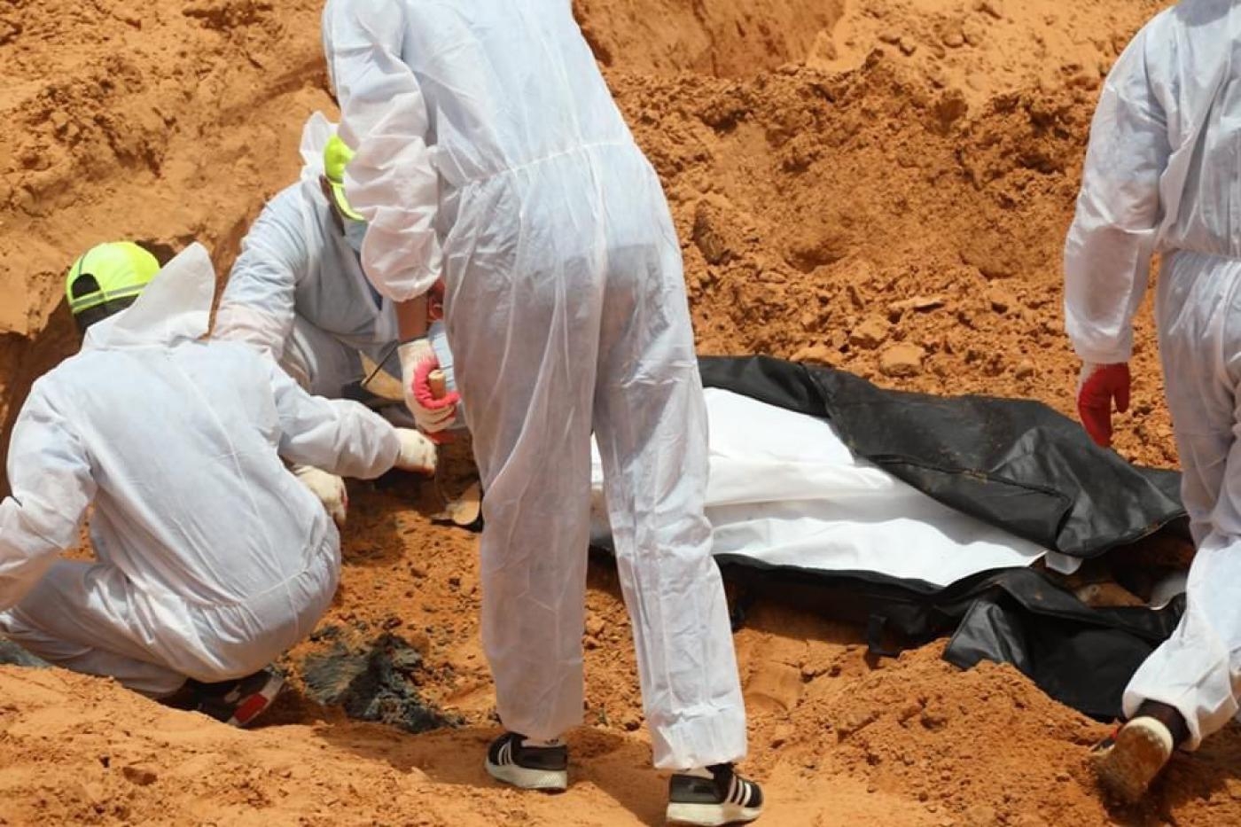 Des membres du Croissant-Rouge libyen et de l’Autorité générale pour la recherche et l’identification des personnes disparues récupèrent des corps dans une fosse commune à Tarhounah (Twitter/@Burkanly)