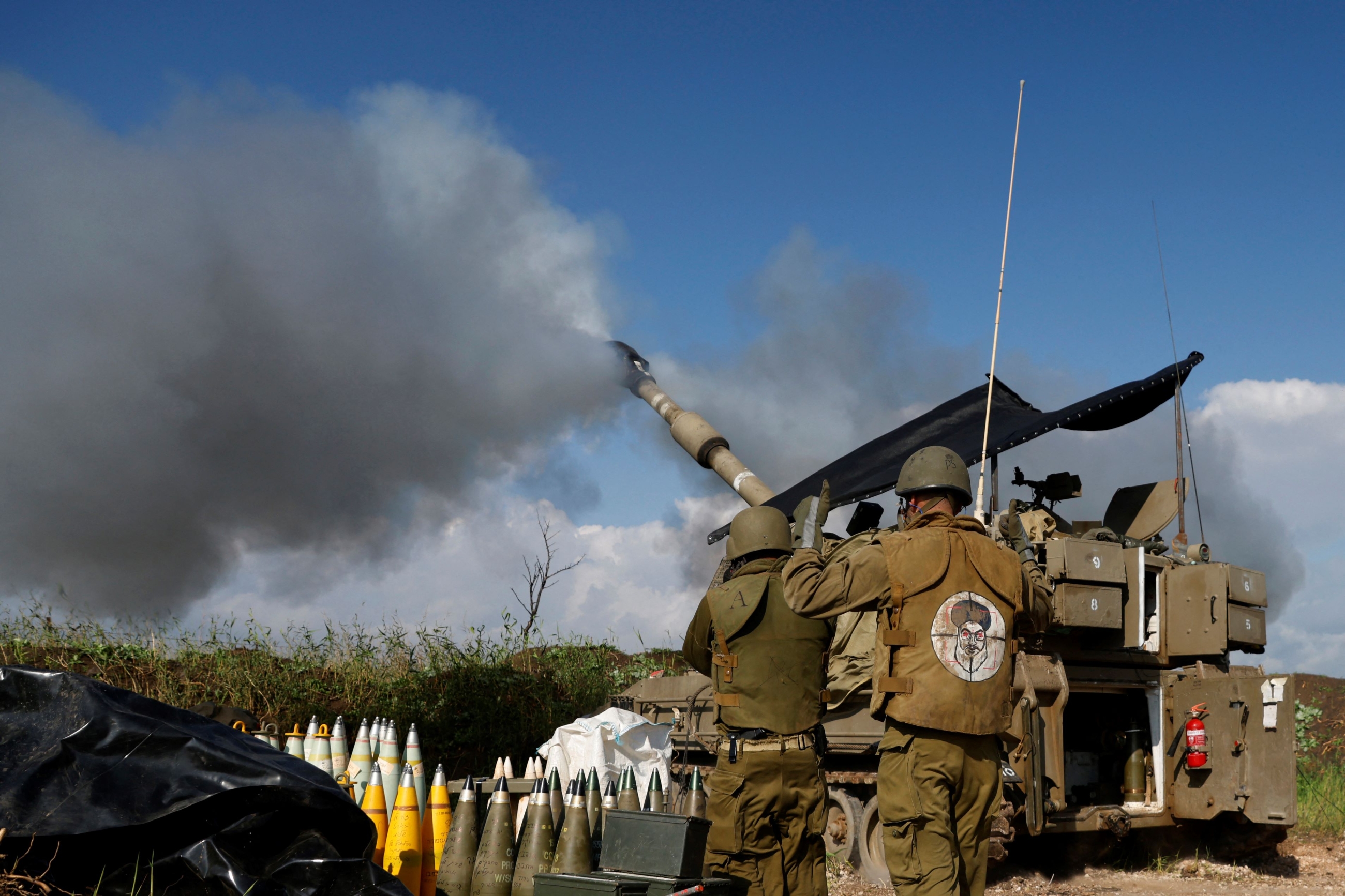 Israeli soldier wearing a patch on the back of his flack jacket showing Lebanon's Hezbollah leader Hassan Nasrallah as a target, stands in front of howitzer in Upper Galilee in northern Israel January 2024, as an artillery unit shells southern Lebanon (Jalaa Marey/AFP)