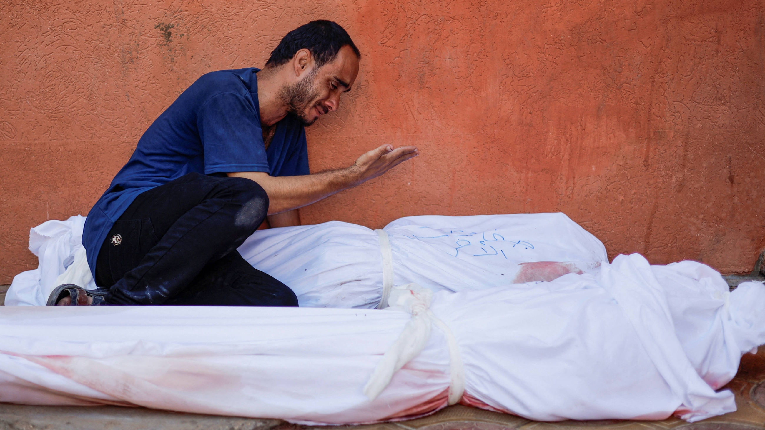 A Palestinian man next to the bodies of his wife and daughter who were killed by Israeli strikes, in Khan Younis in the southern Gaza Strip, 26 October 2023 (Reuters)