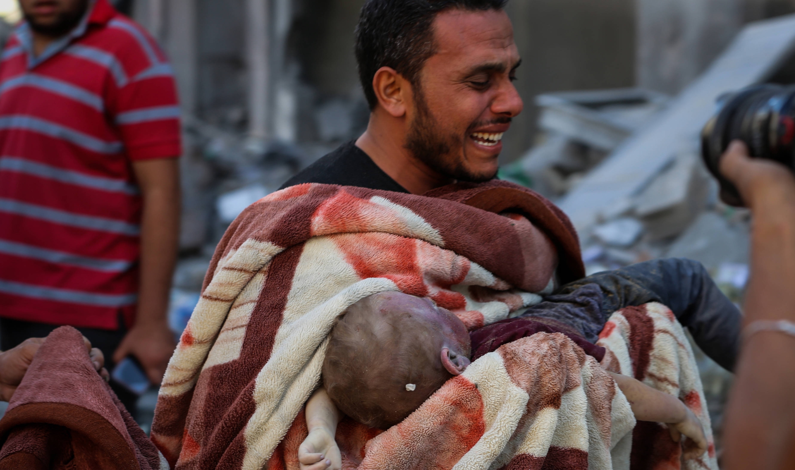Un homme pleure après avoir sorti un enfant des décombres, le 12 octobre 2023 à Gaza (MEE/Mohammed Hajjar)