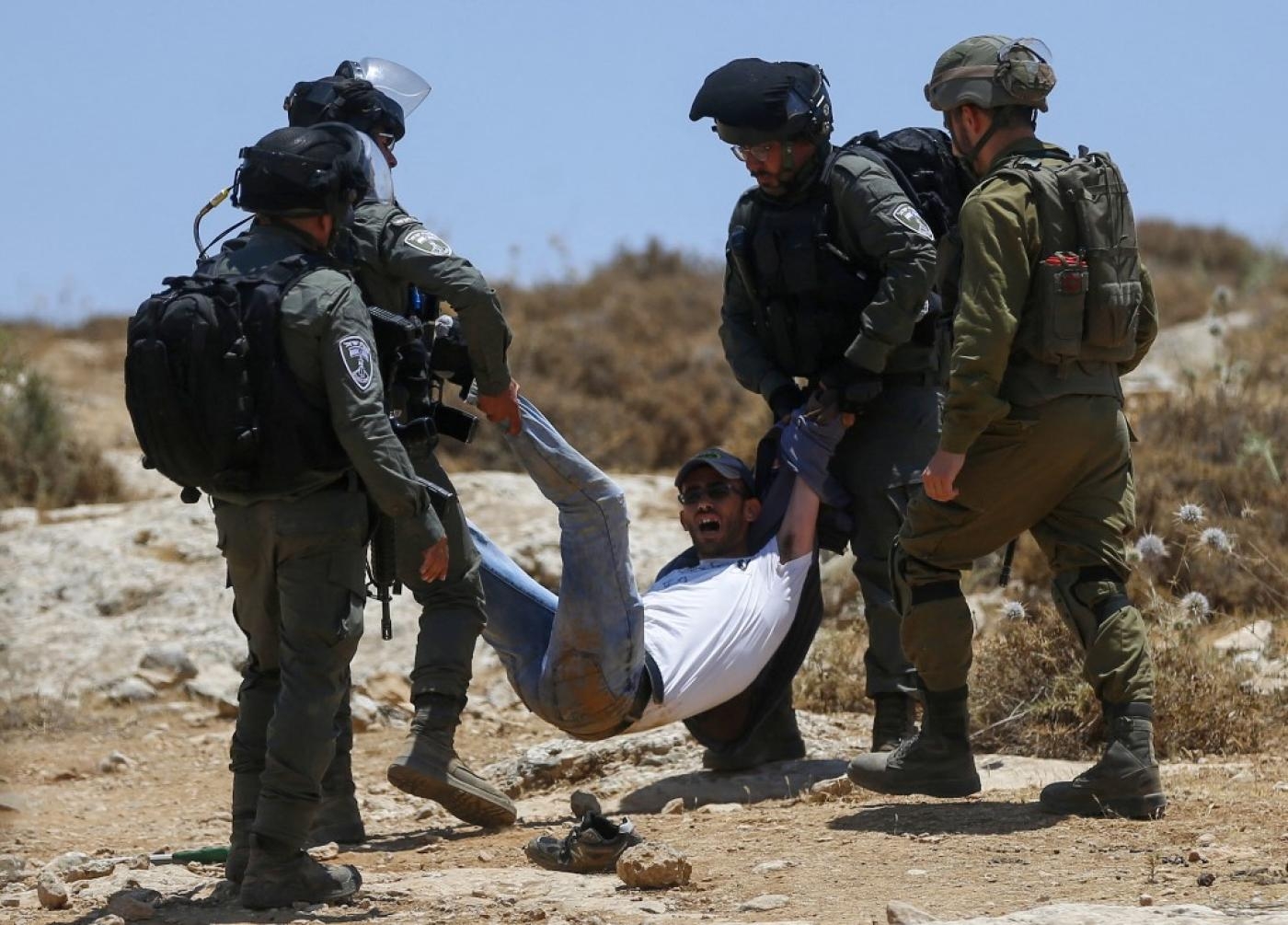 Les forces israéliennes déplacent de force un Palestinien lors d’une manifestation à Masafer Yatta, en Cisjordanie occupée par Israël, le 1er juillet 2022 (AFP)