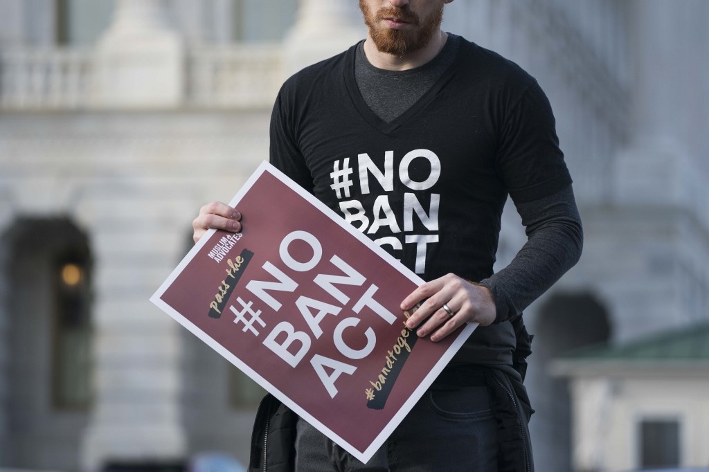 A protester carries a 'No Ban Act' placard