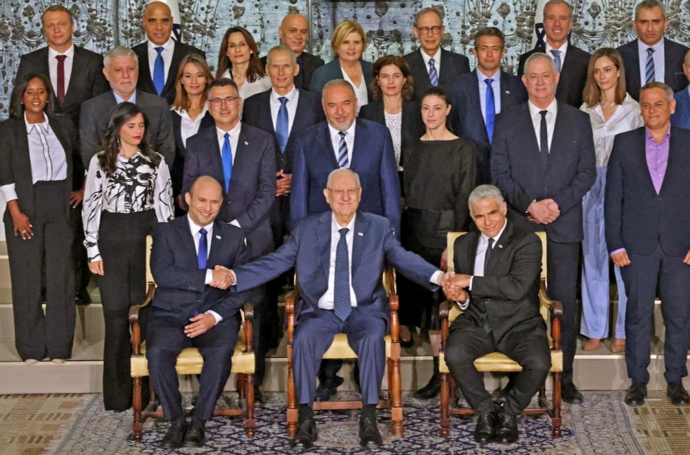 Le président sortant Reuven Rivlin entouré de Naftali Bennett (à gauche) et Yaïr Lapid (à droite) dans la résidence du président à Jérusalem, le 14 juin 2021 (AFP)