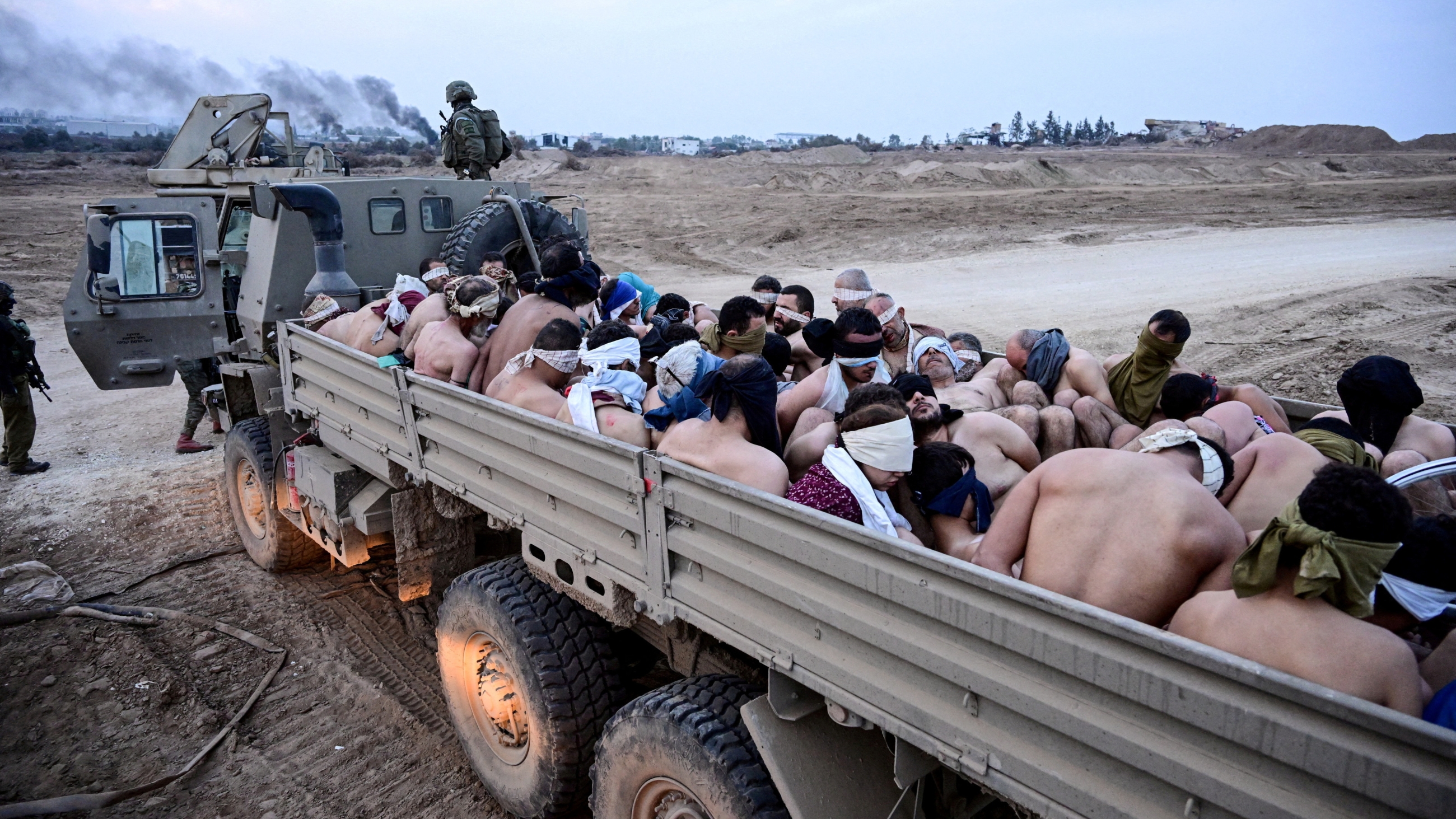 Israeli forces transfer blindfolded, stripped, and handcuffed Palestinian men arrested and detained, in the Gaza Strip, on 8 December 2023 (Yossi Zelige/Reuters)