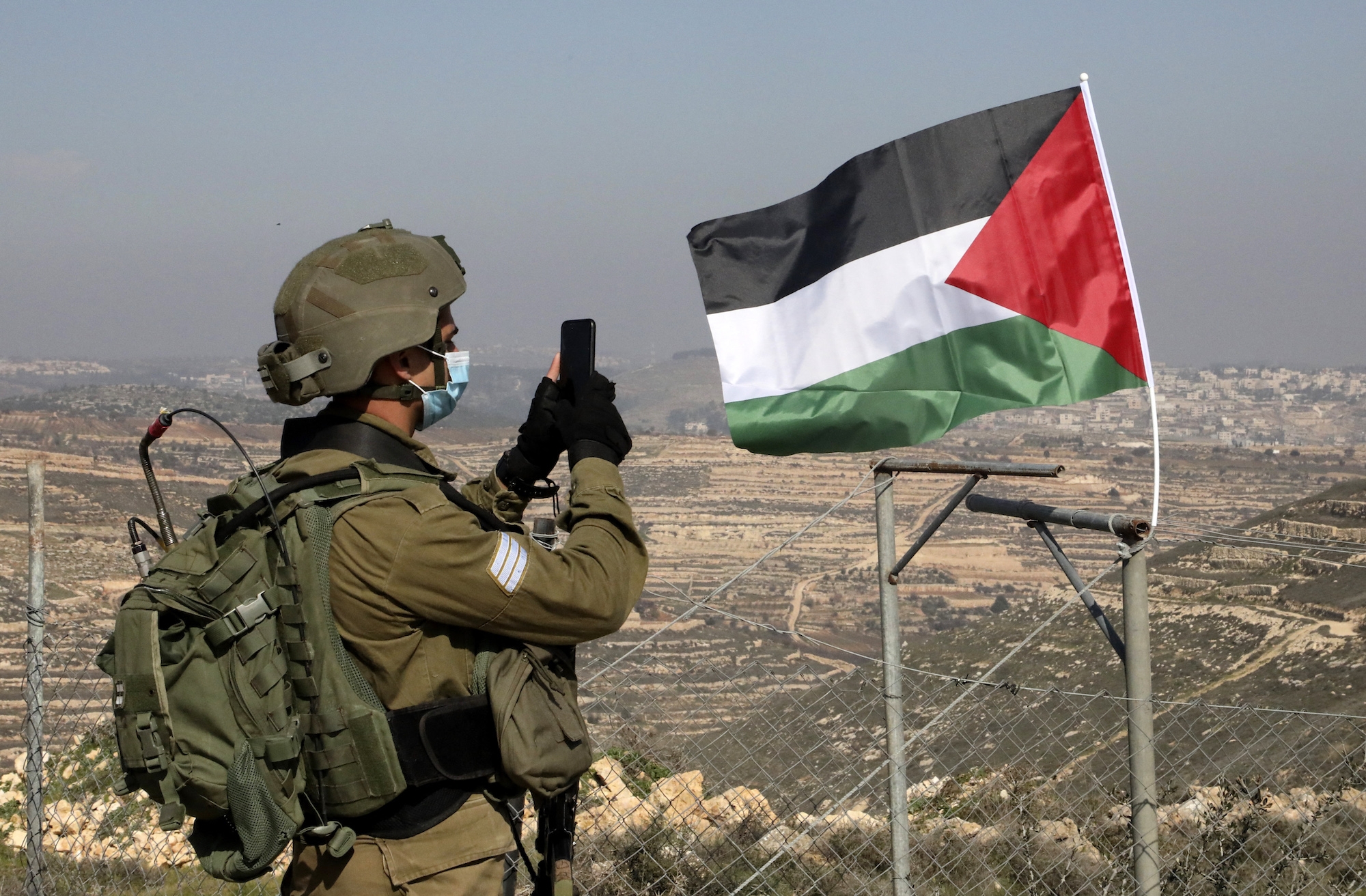 Israeli soldier stands near Palestinian flag in West Bank AFP