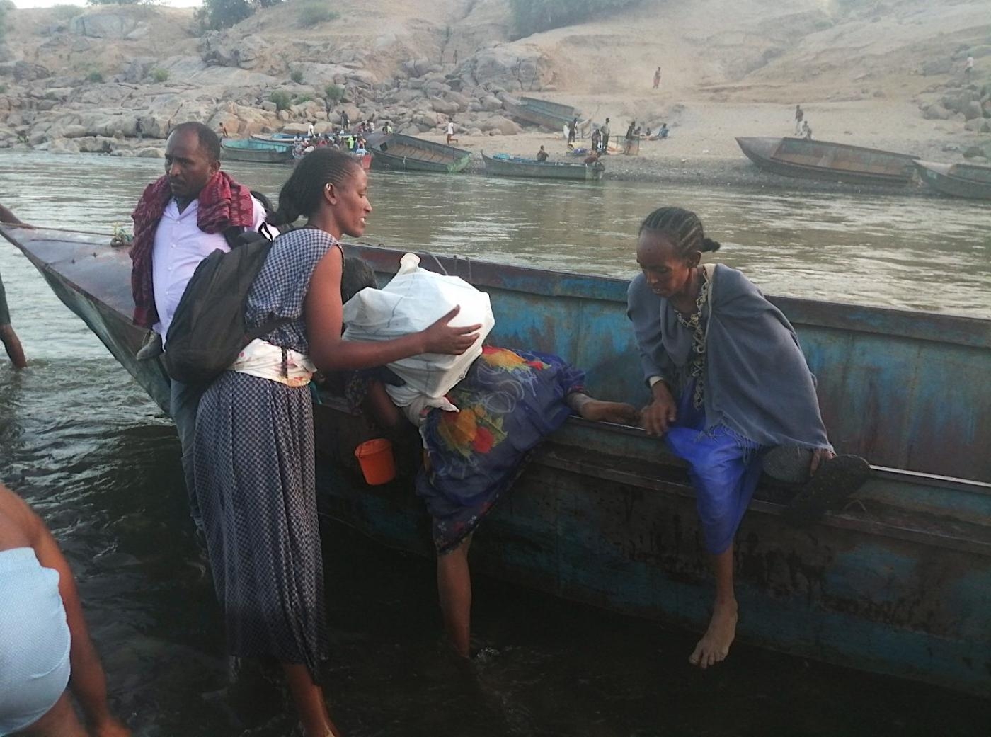 Des Éthiopiens fuyant la région du Tigré descendent d’un bateau après avoir traversé la frontière pour arriver à Hamdayet, leur point d’entrée au Soudan (MEE/Mohammed Amin)