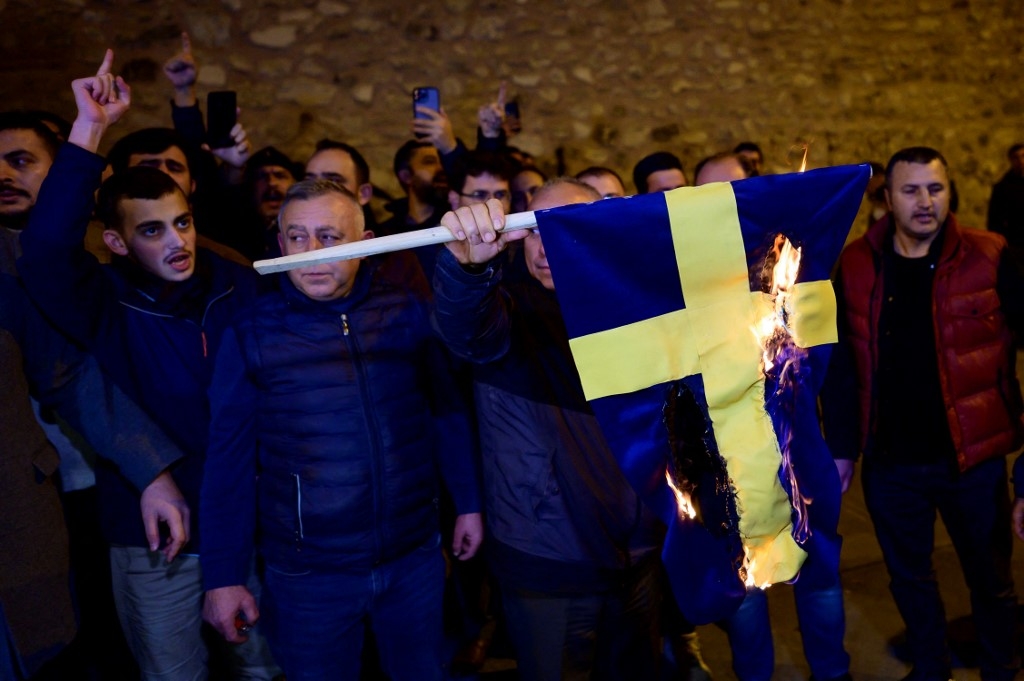 Protesters burn the national flag of Sweden as they demonstrate in front of the Consulate General of Sweden after Rasmus Paludan, leader of Danish far-right political party Hard Line and who also has Swedish citizenship burned a copy of the Koran near the Turkish Embassy in Stockholm, in Istanbul, on January 21, 2023. (AFP)
