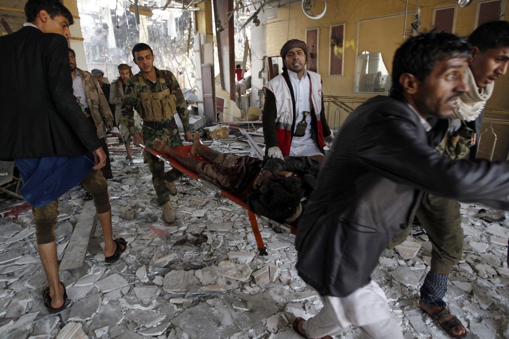 Yemeni rescue workers carry a victim on a stretcher amid the rubble of a funeral hall hit by Saudi-led coalition airplanes in Sanaa on 8 October 2016 (AFP)