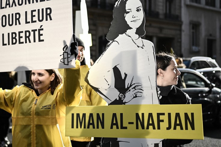 People hold a sign reading "honk for women's rights" and cutouts of a woman incarcerated during a demonstration organised by Amnesty International outside the Saudi embassy in Paris, on 8 March 2019
