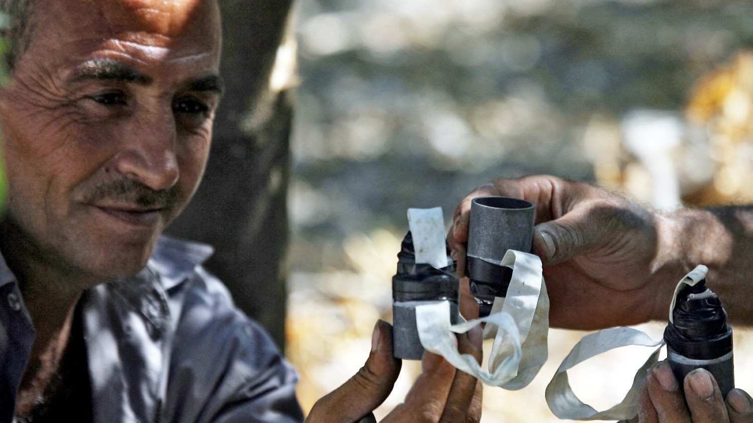A man shows detonated cluster bombs in a field in the southern Lebanese village of Deir Qanun an-Nahr on 7 September 2006.