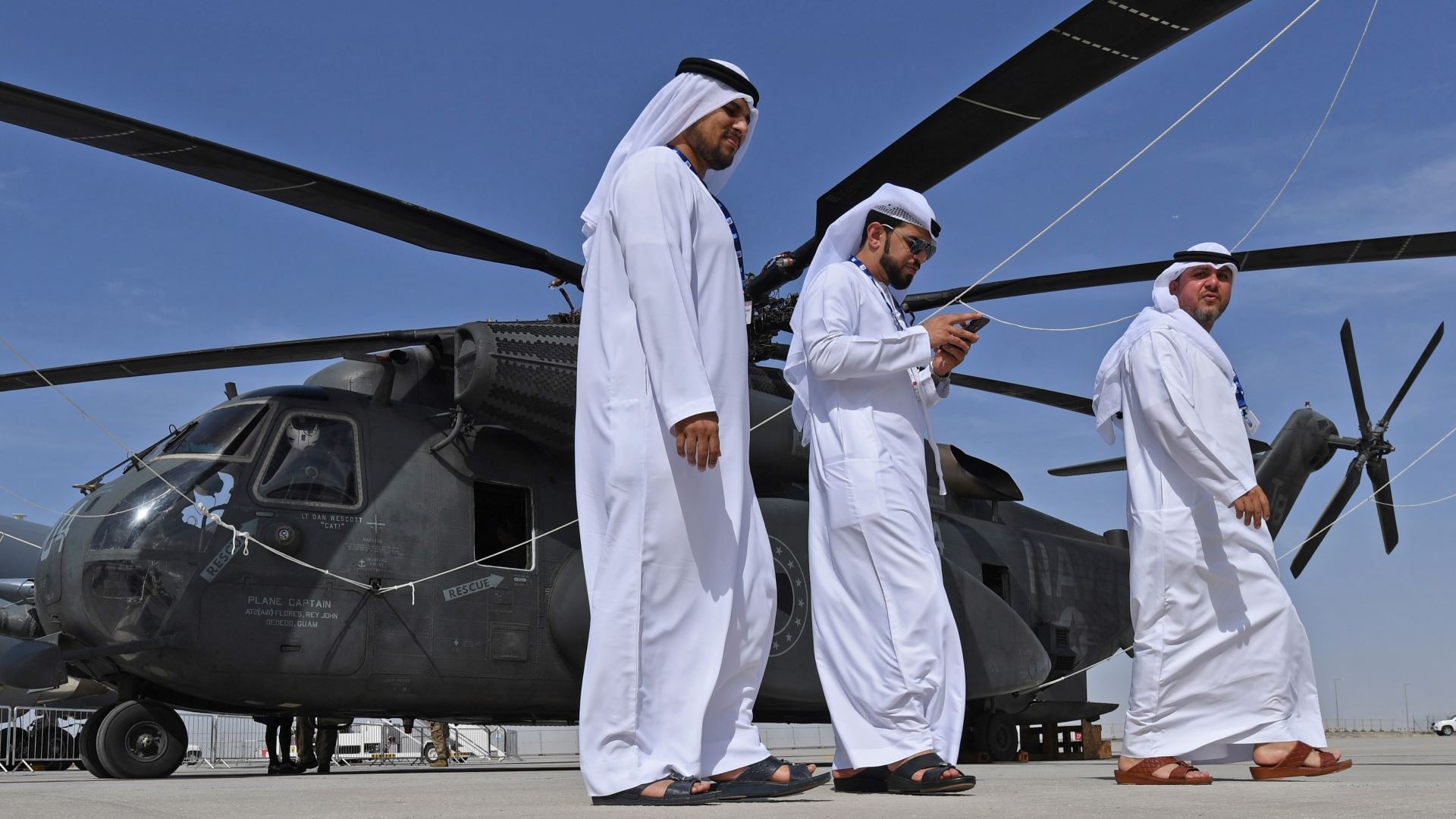Emirati men walk past a Sikorsky CH-53E Super Stallion at the Dubai Airshow on 18 November 2019.