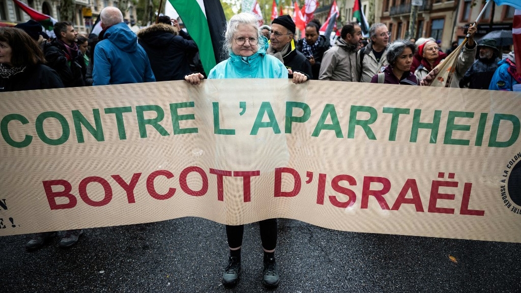 A protester holds a banner reading “Against apartheid, boycott of Israel” during a demonstration in solidarity with Palestinians in Toulouse, France, on 4 November 2023 (Lionel Bonaventure/AFP)
