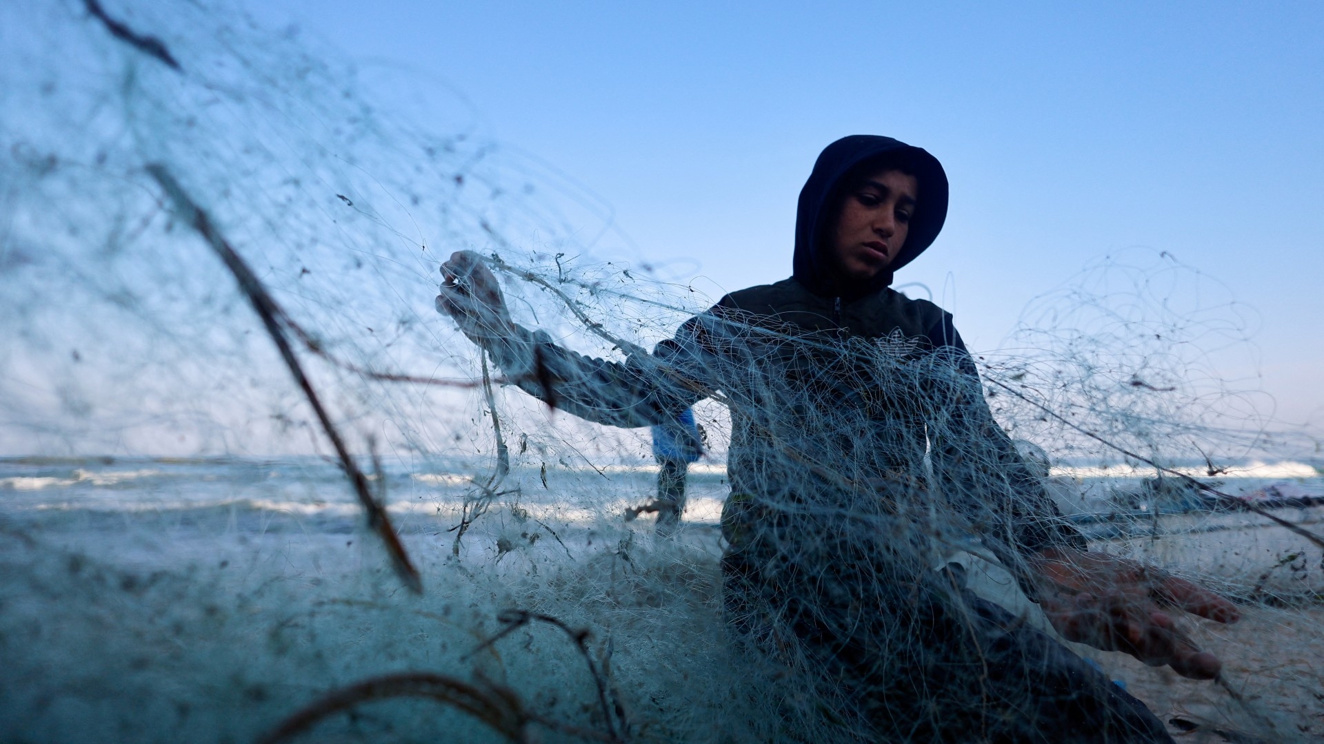 A Palestinian boy looks at a fishing net on the beach in Rafah, in the southern Gaza Strip, 16 January (Reuters/Mohammed Salem)