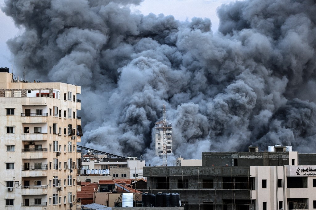 Une colonne de fumée s’élève au-dessus des bâtiments de Gaza, le 7 octobre 2023, lors d’une frappe aérienne israélienne (AFP/Mahmud Hams)